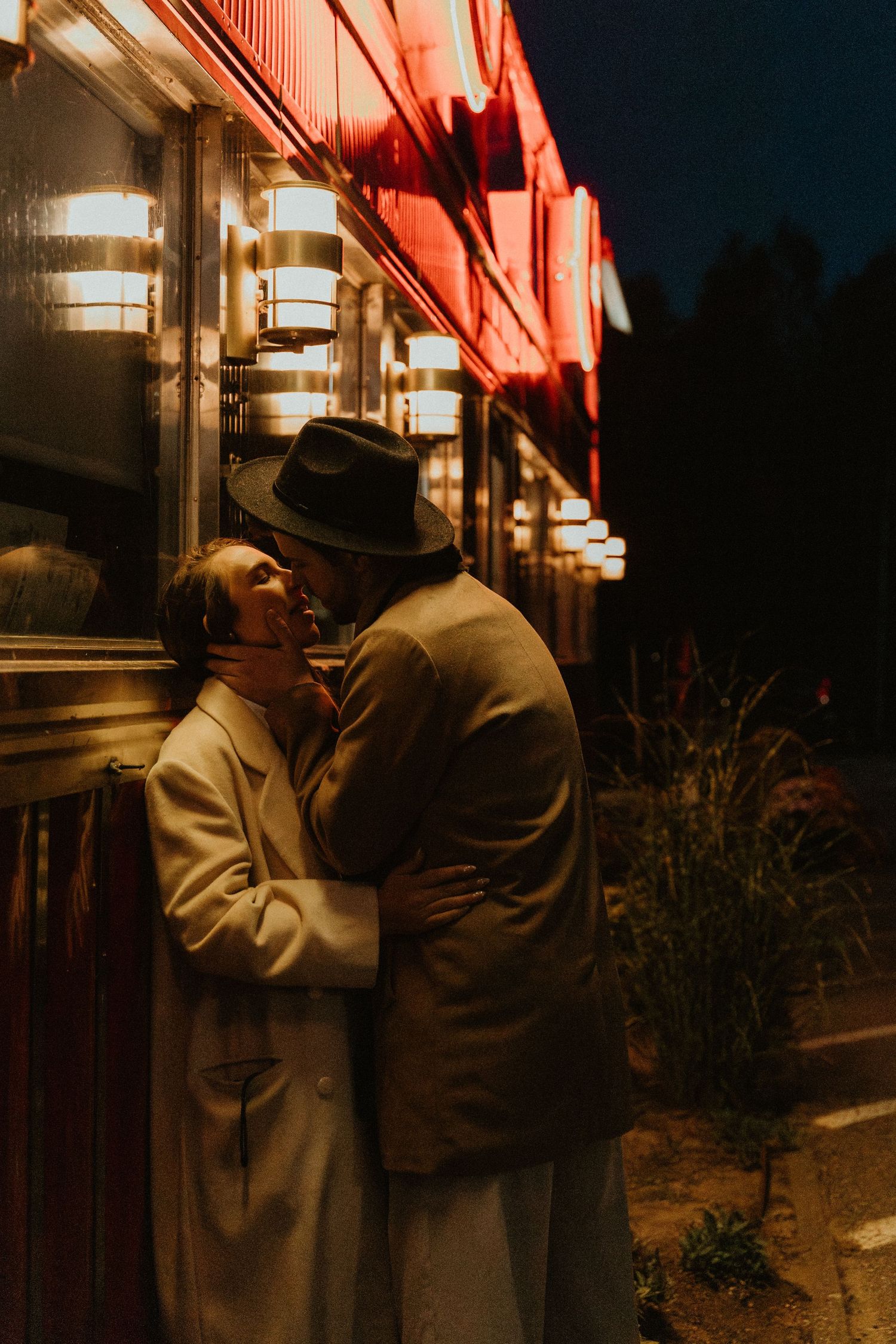 A romantic evening scene under warm red lighting outside a building.