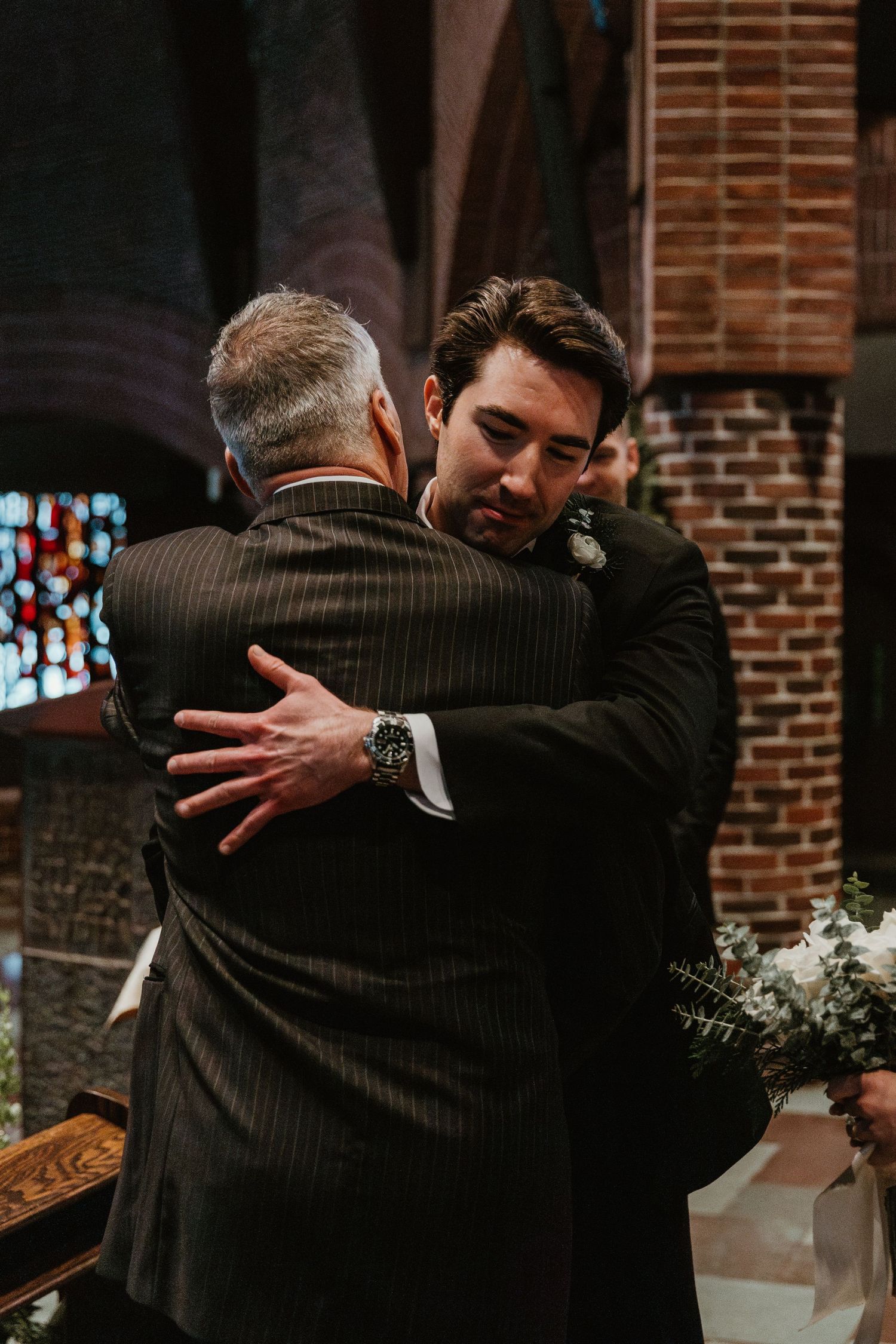 Emotional embrace between two people during a wedding ceremony in a brick church.