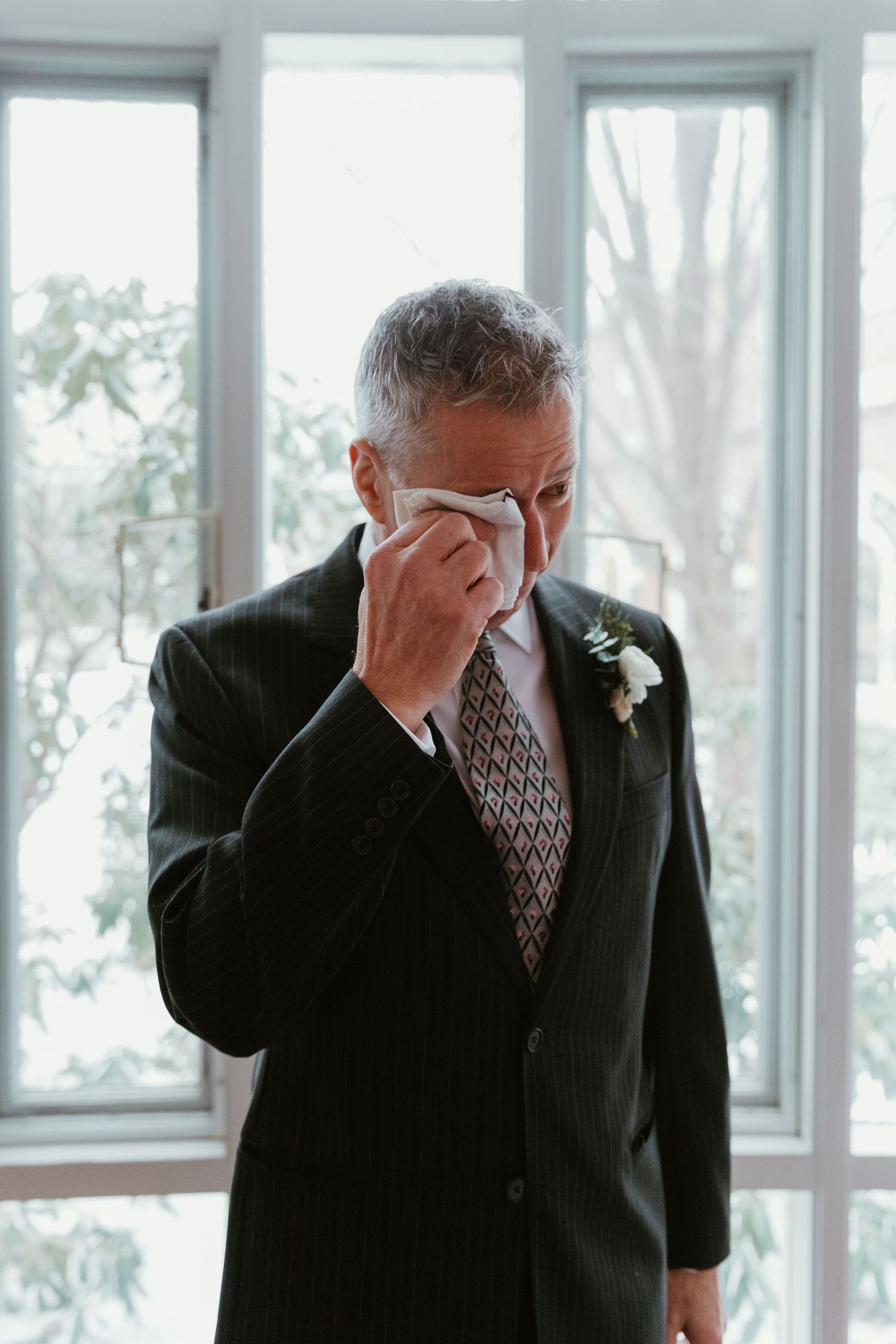 A person in formal attire wipes tears during an emotional wedding moment.