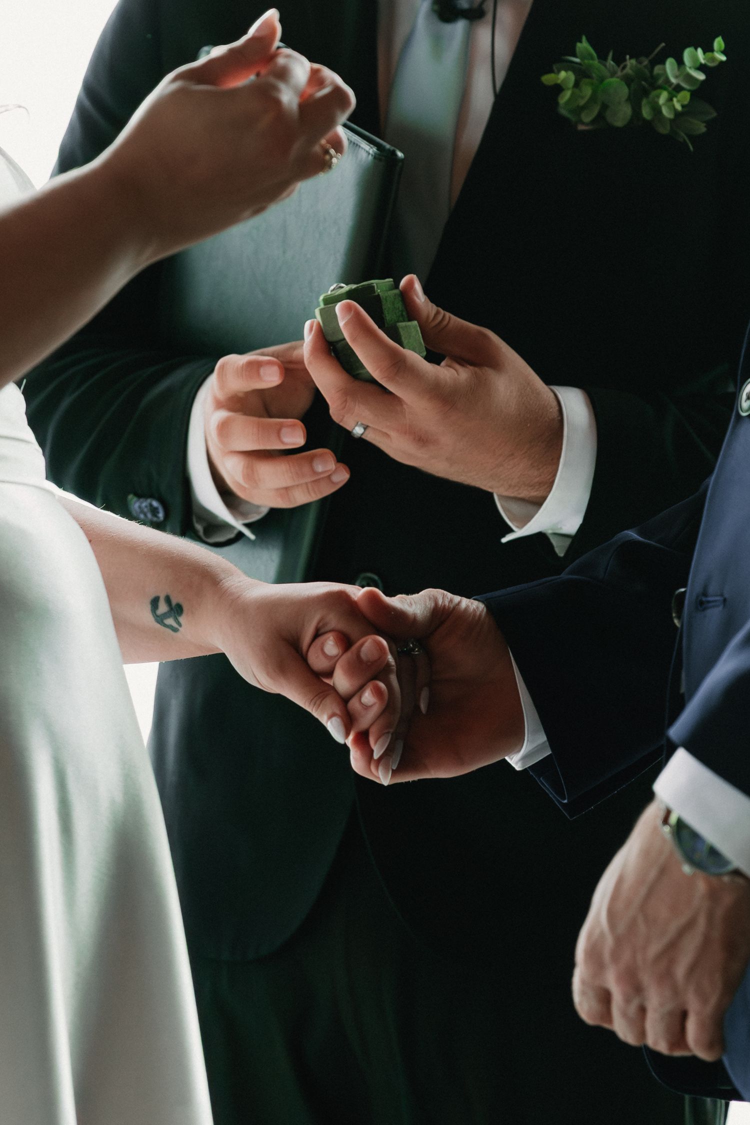 Detailed view of wedding ring exchange between two people in formal attire.