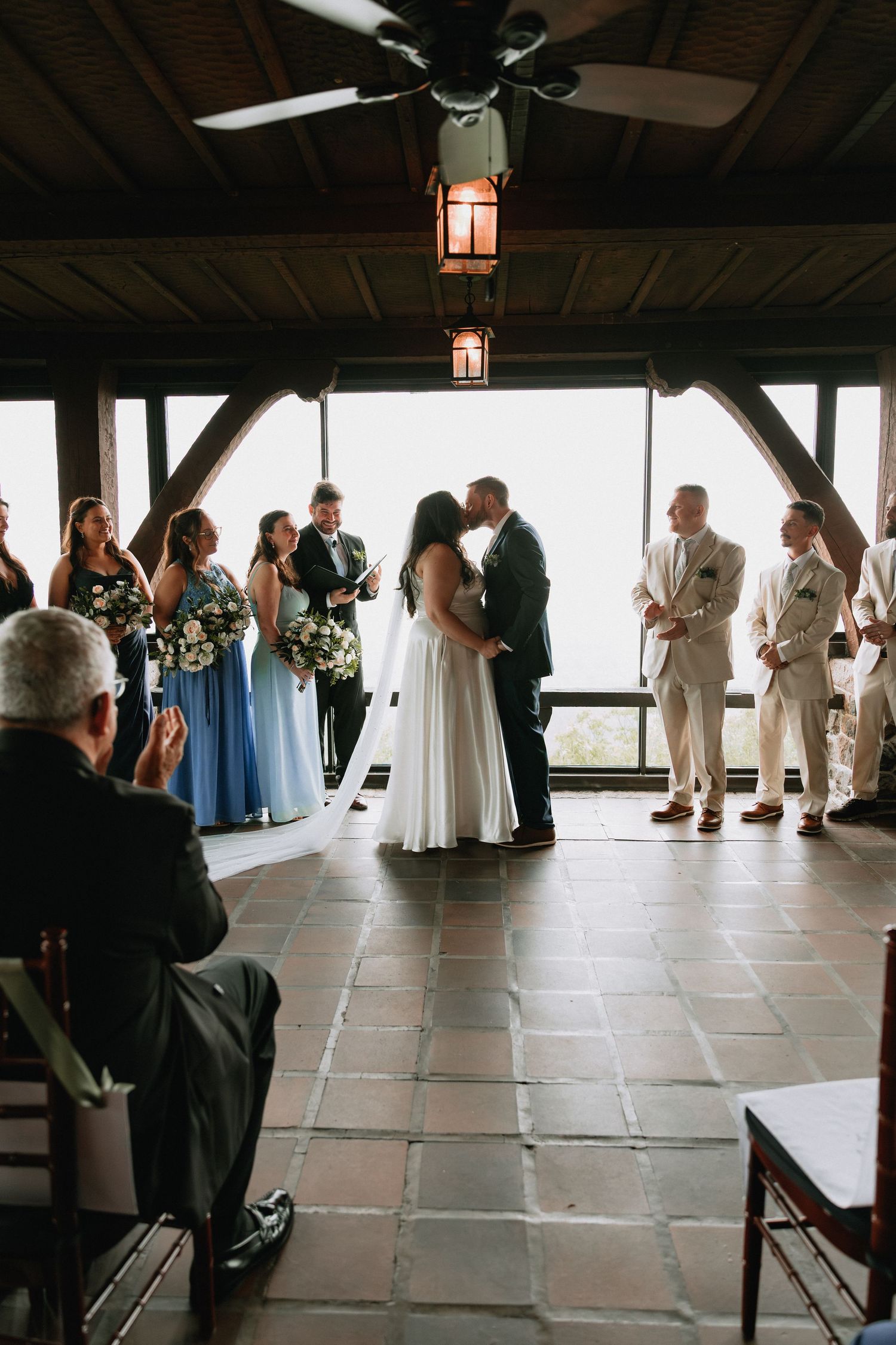 Wedding guests gathered in a rustic venue with tile flooring and lantern lighting.