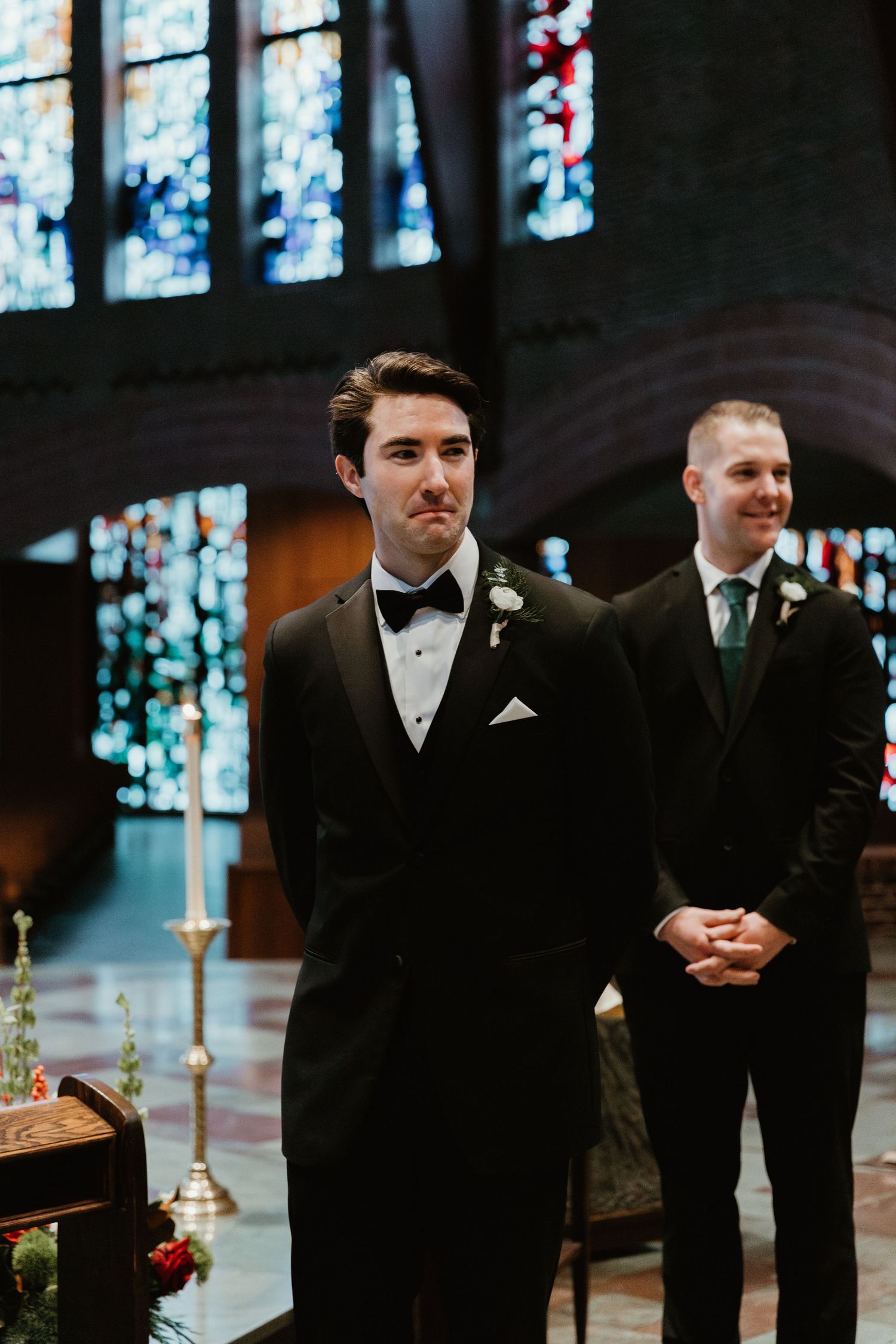 Wedding ceremony in a church with stained glass windows and altar decorations.