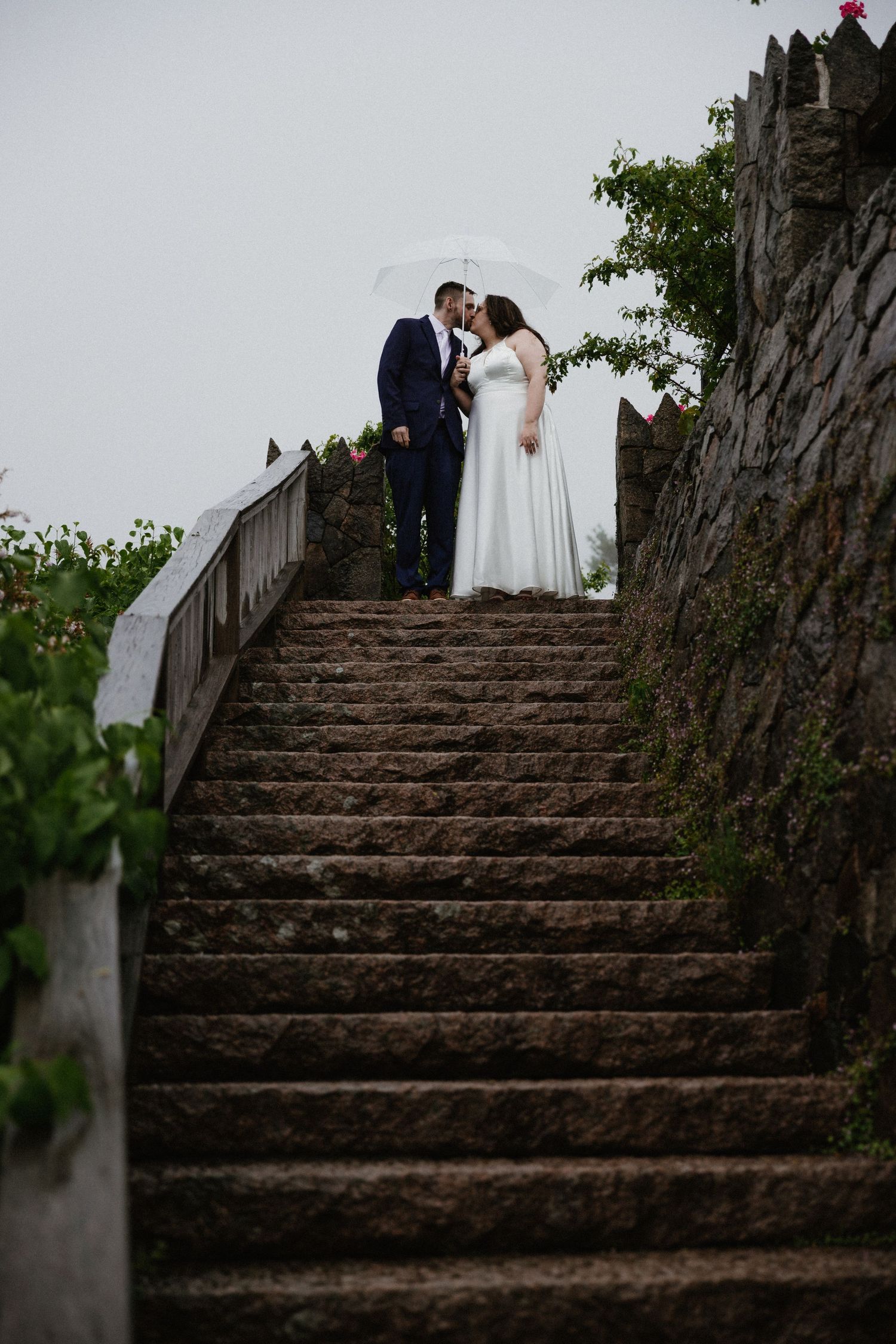 A romantic moment captured on rustic stone steps surrounded by lush greenery.