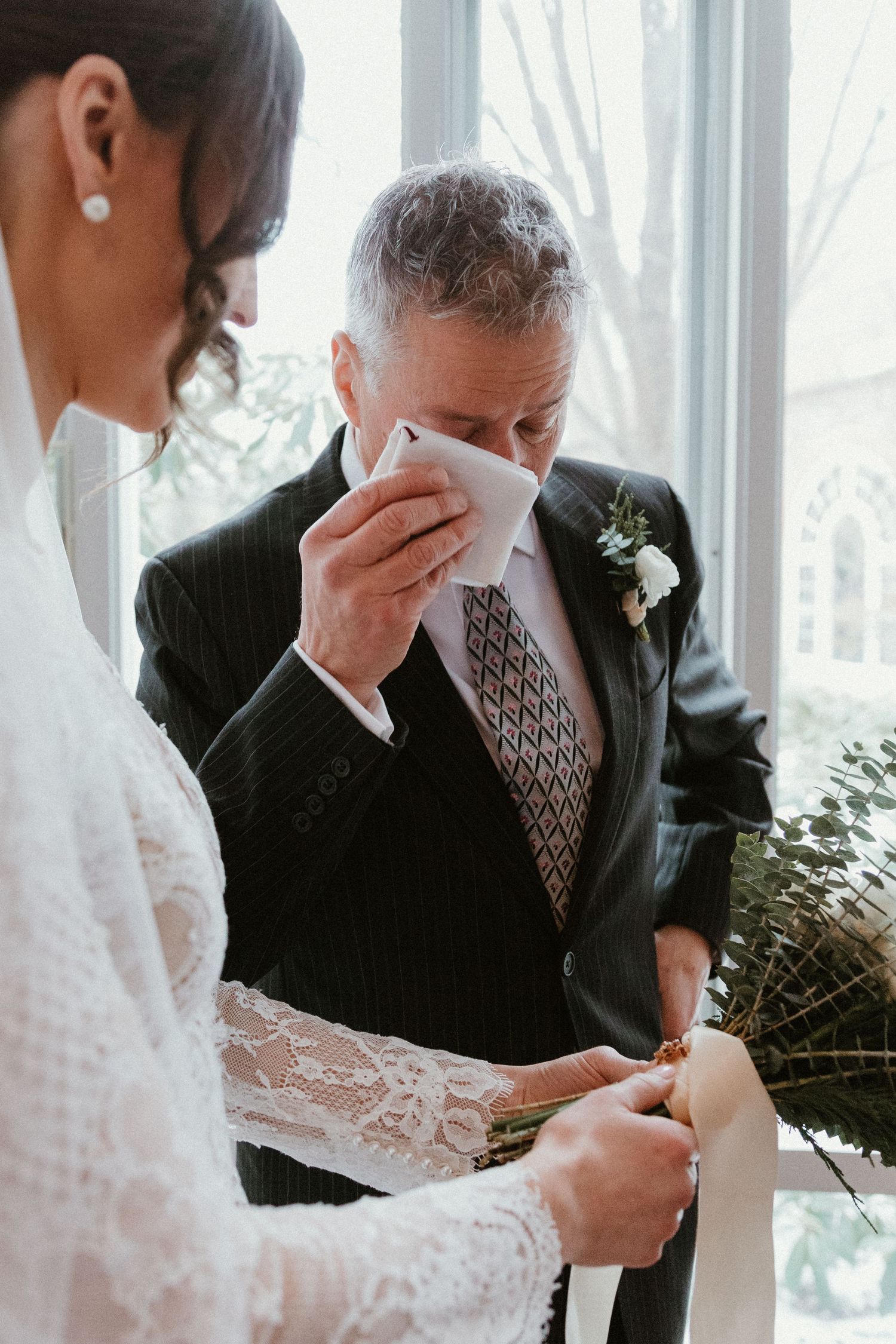 Emotional moment captured during wedding ceremony with lace and floral details.