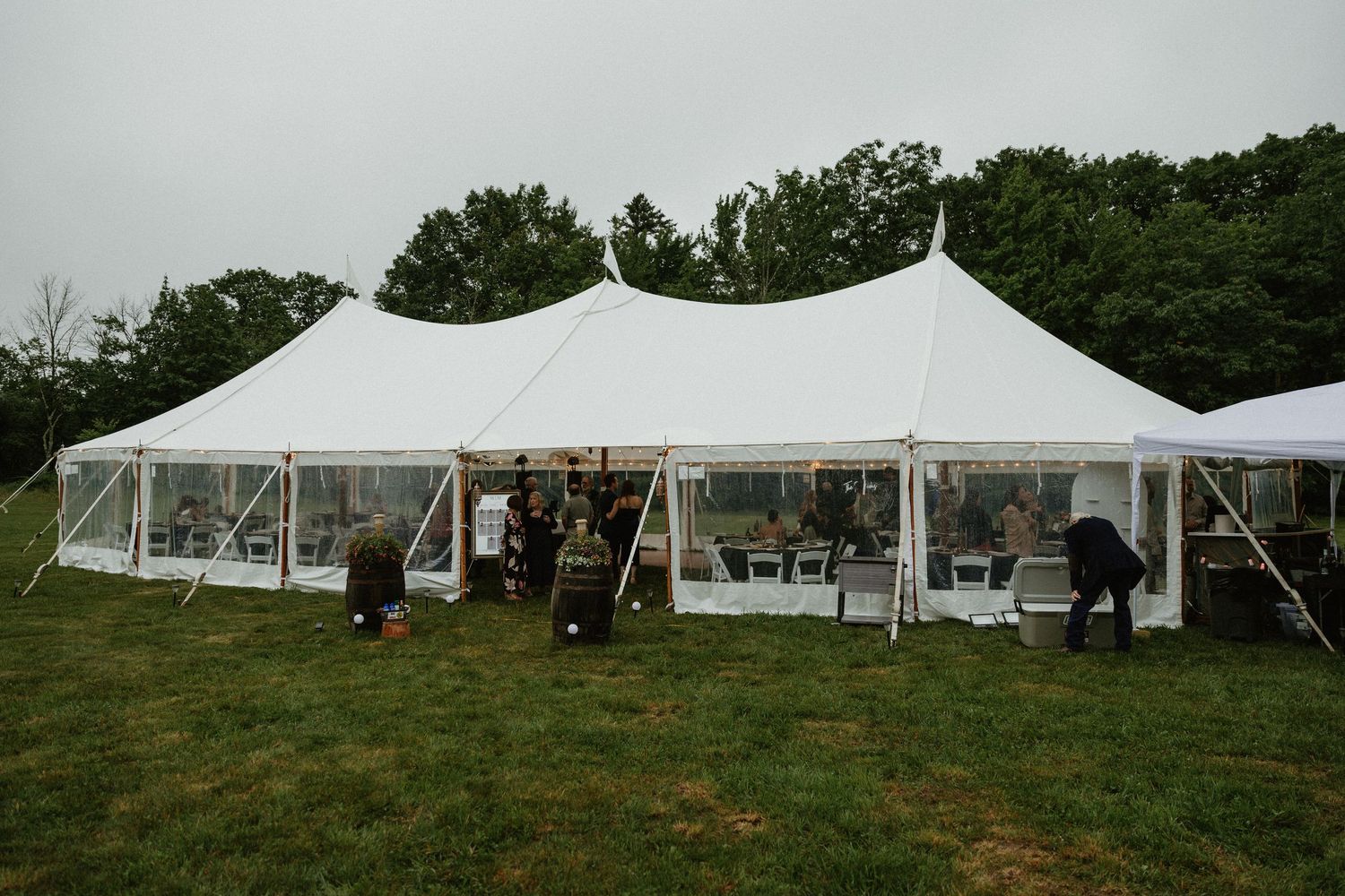 White wedding tents set up on a grassy hillside for an outdoor reception event.