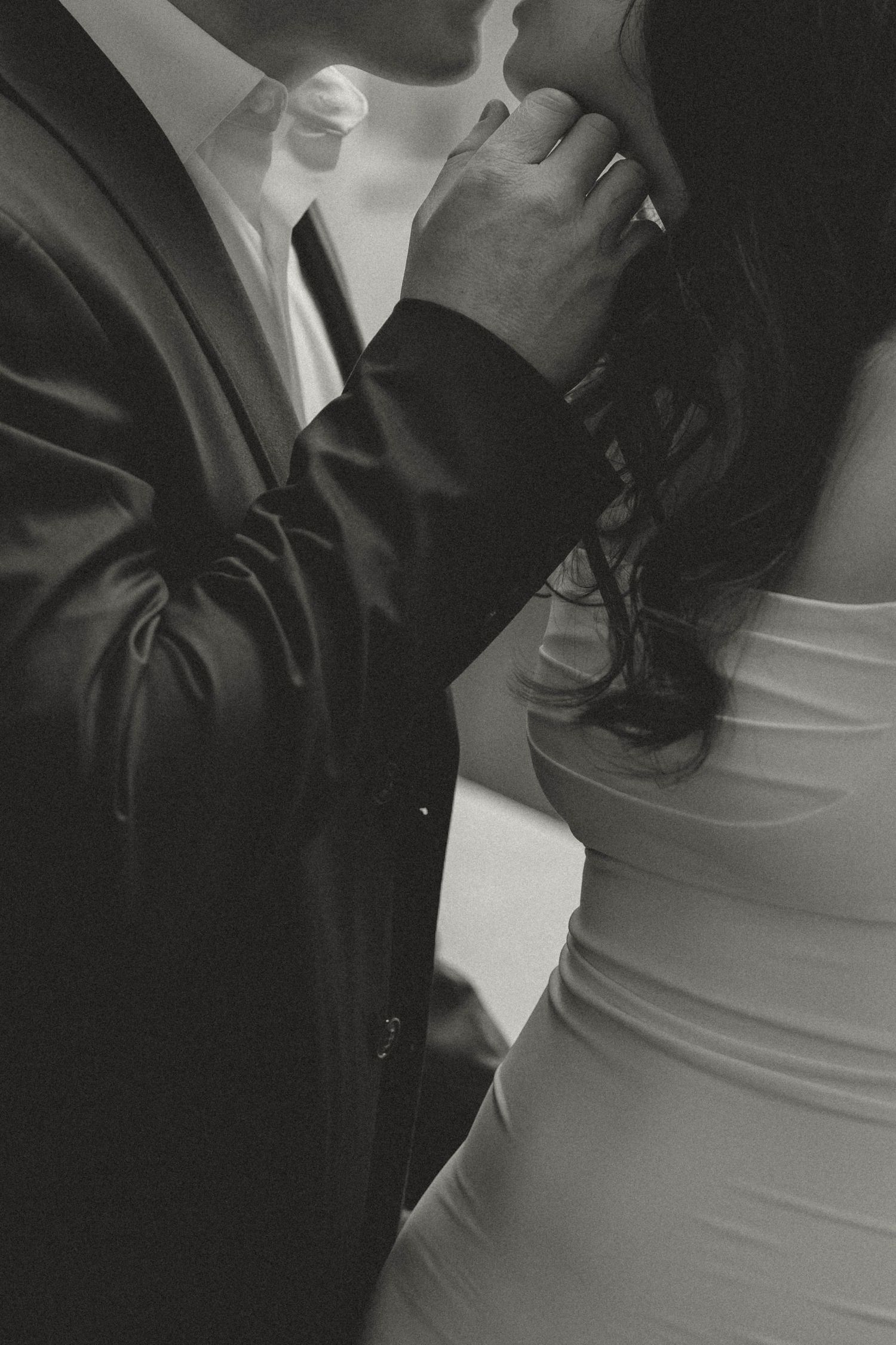 Close-up black and white photo of a couple in formal attire standing close together at a wedding or formal event.