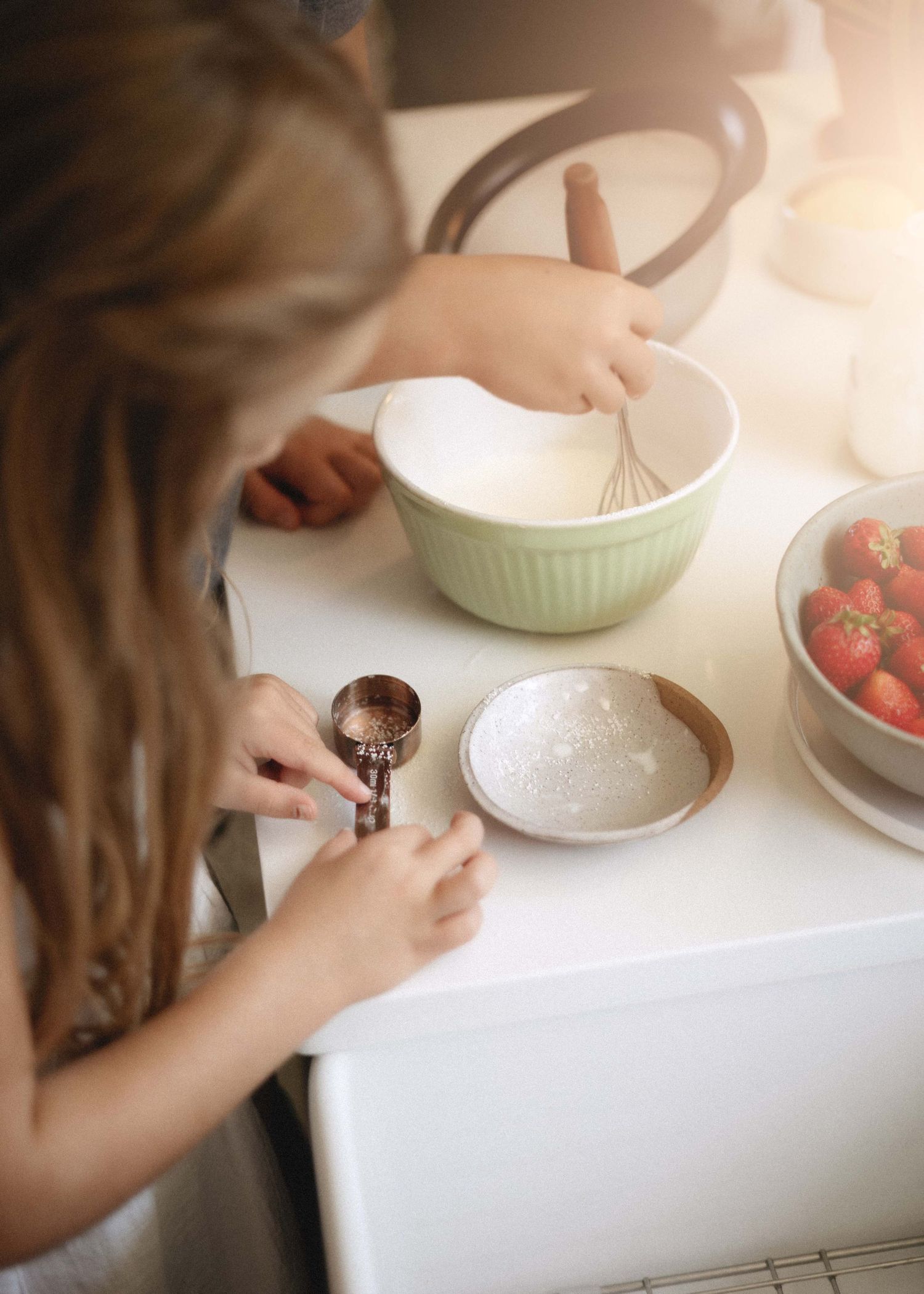 Hands mixing cream in a light green mixing bowl during the food preparation process.