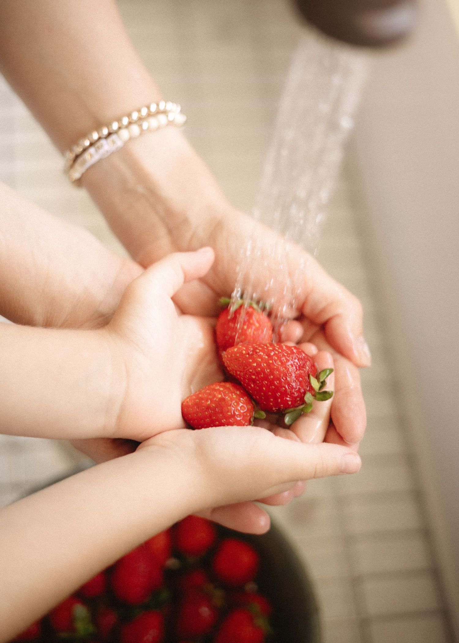 Hands holding fresh red strawberries under a stream of water in a sequence of photos showing sharing and exchange between people.