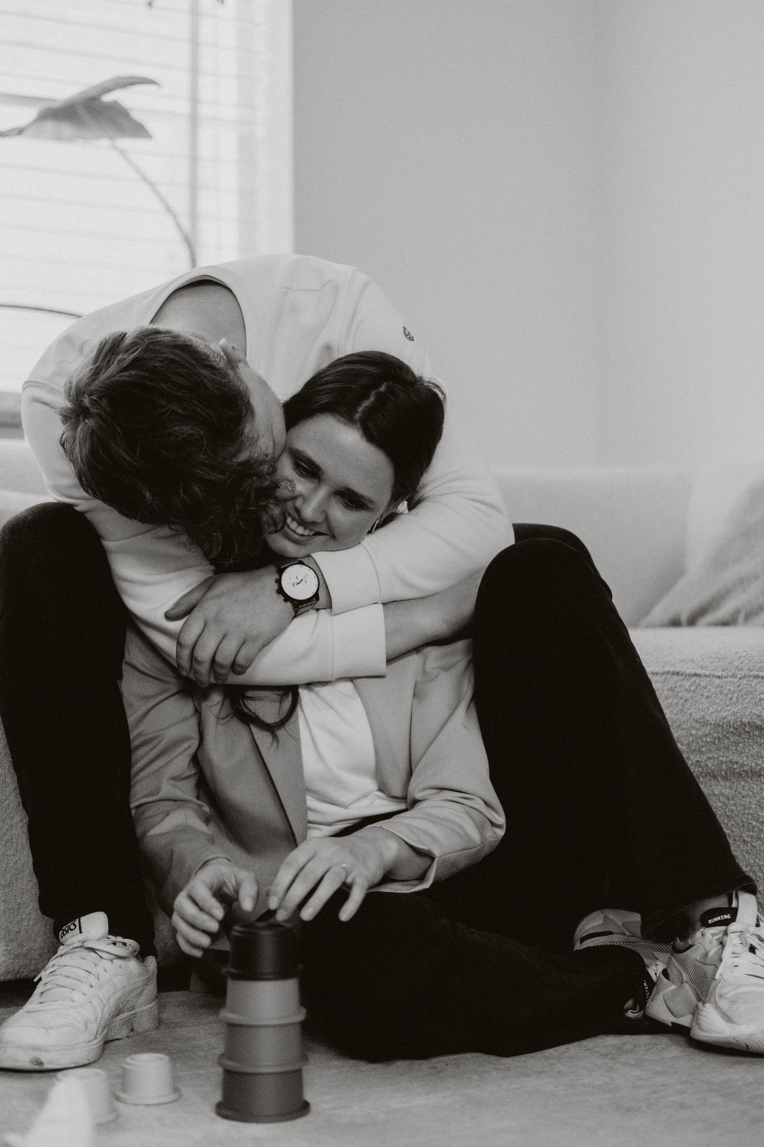 Black and white photo of a couple sharing a warm embrace while sitting on the floor.
