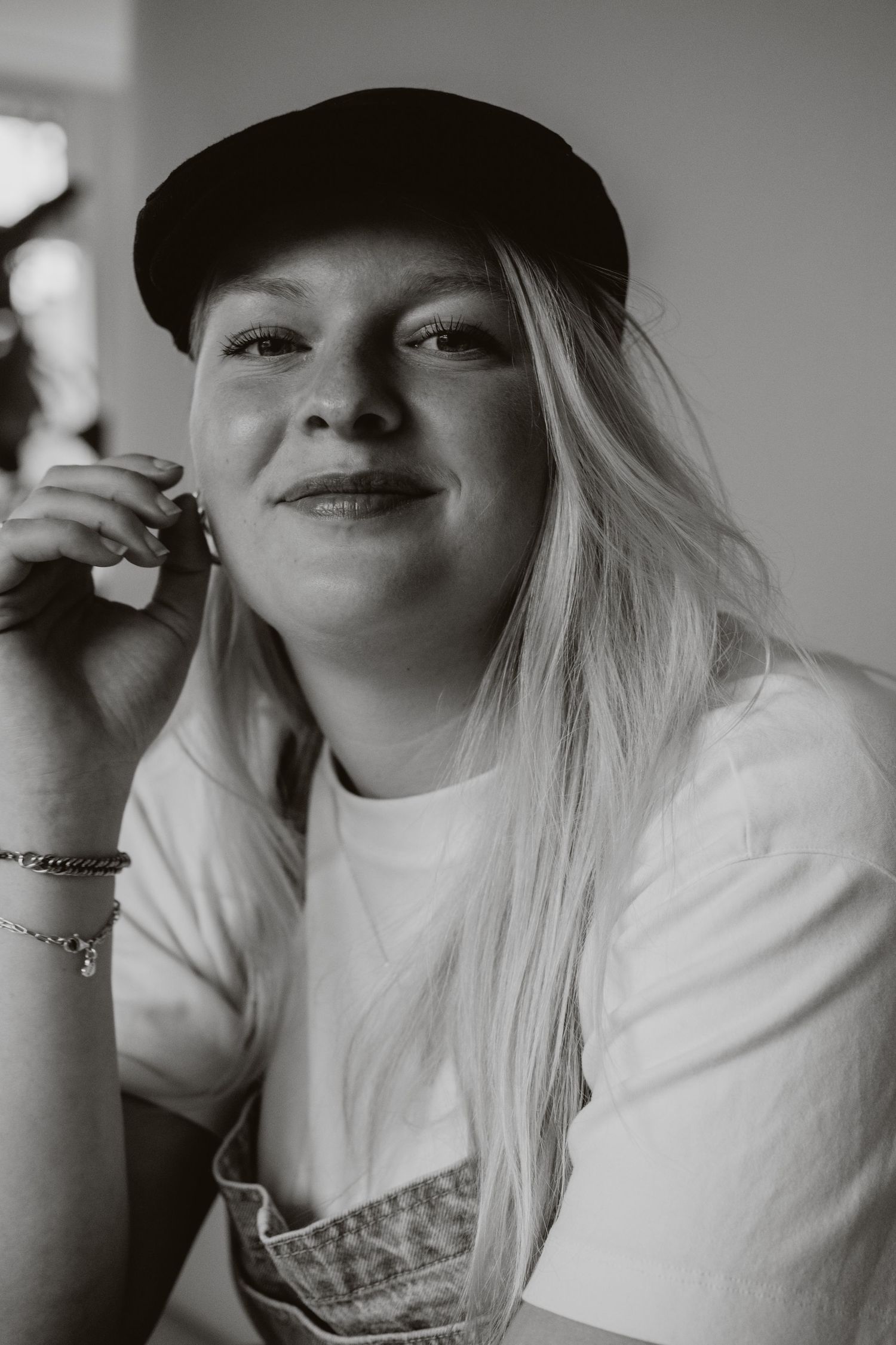 Black and white portrait of a smiling blonde woman in a cap and white t-shirt.