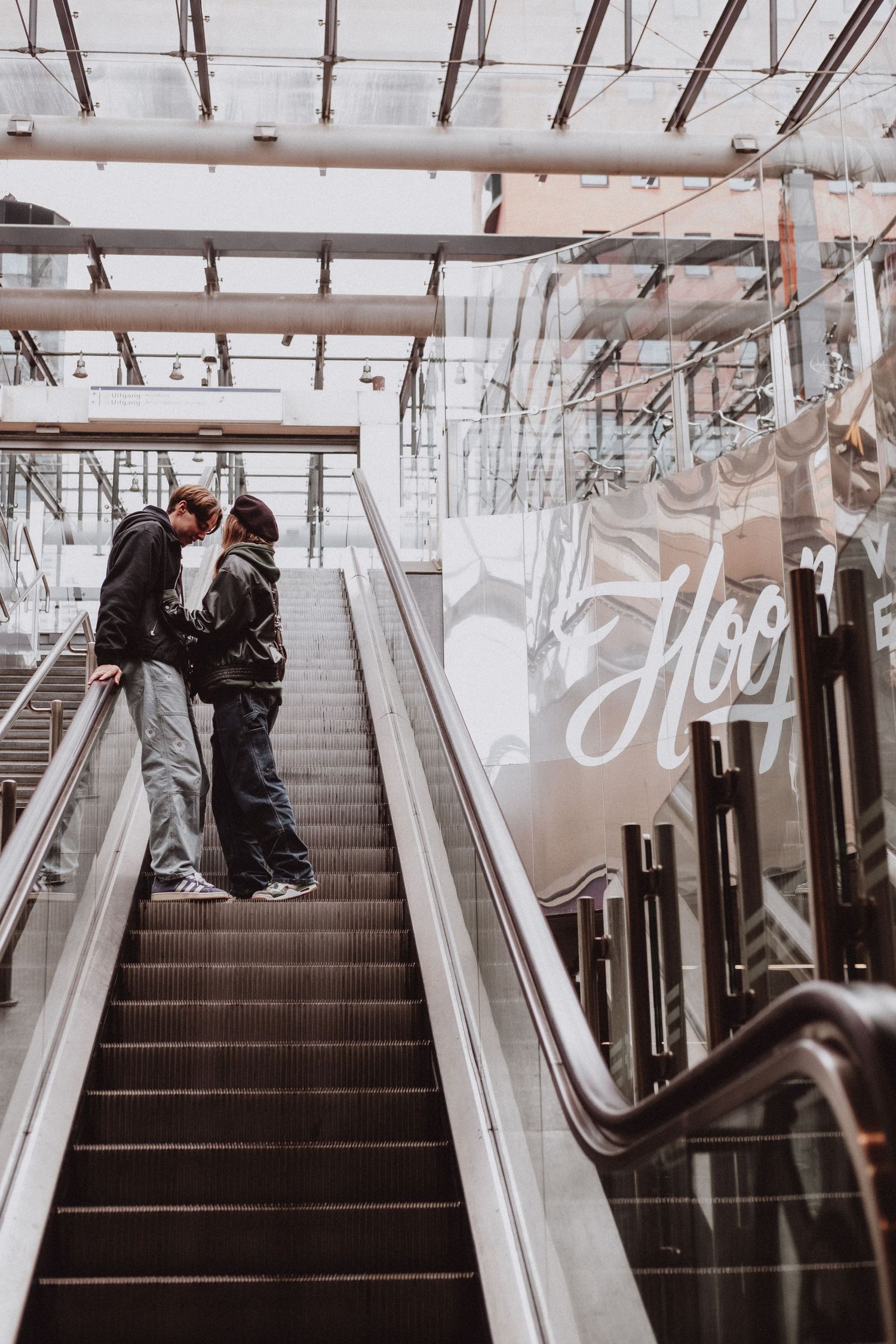 Young couple sharing a kiss on an escalator inside a modern shopping center.