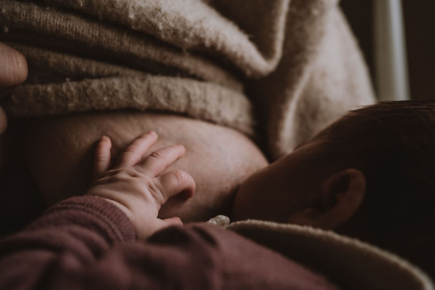 Kleine handjes op moeders borst terwijl de newborn drinkt