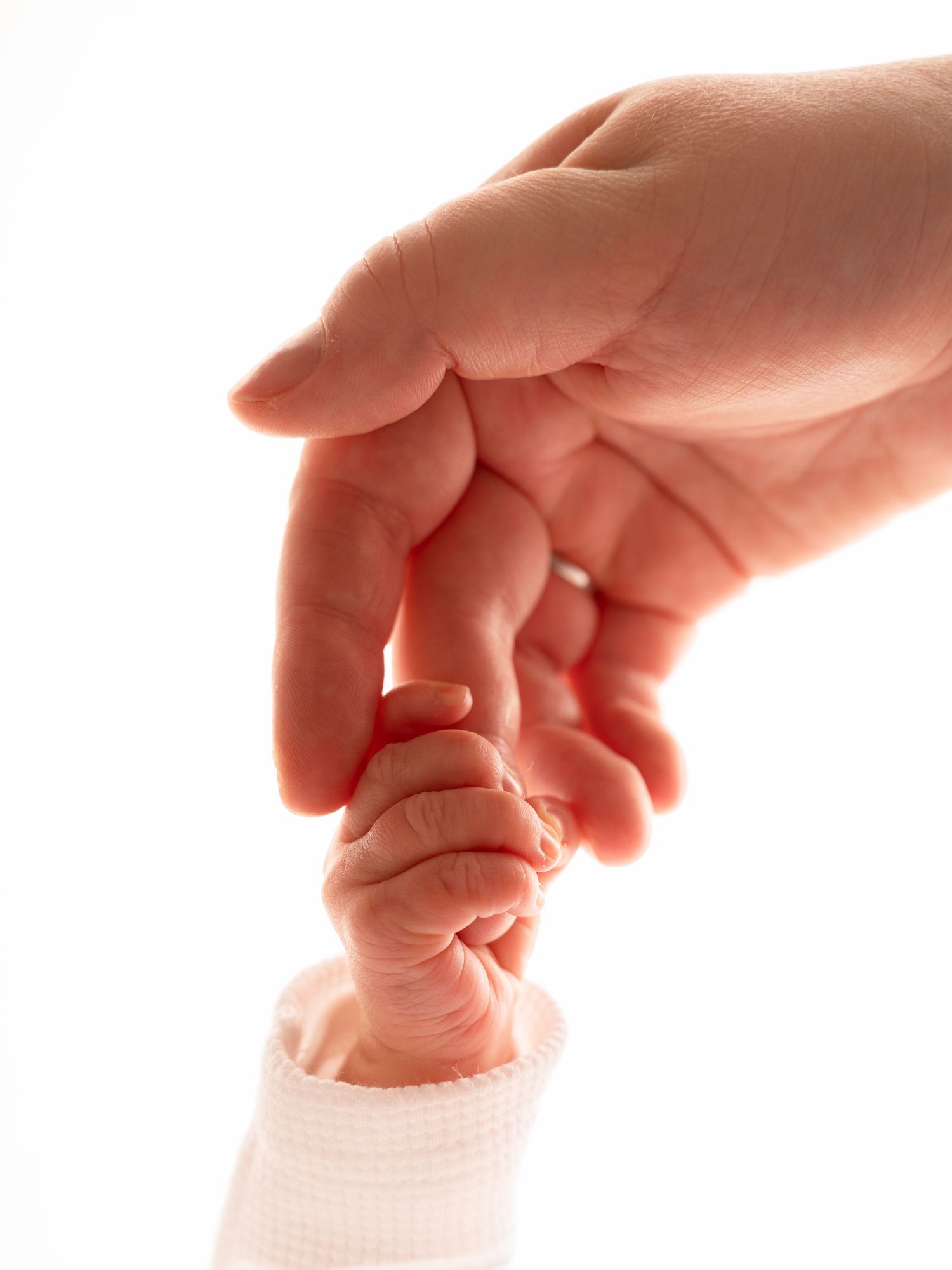 A baby's tiny hand gripping an adult's finger, symbolizing love, trust, and the bond between parent and child.