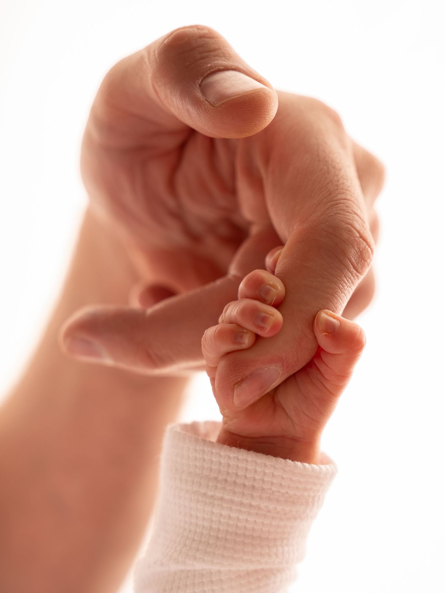 A tiny newborn baby hand grasping an adult finger, symbolizing love and parental bond.