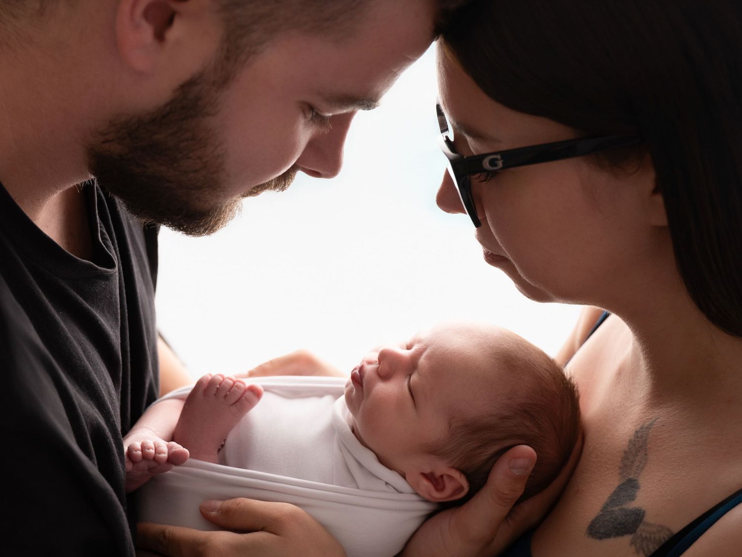 New parents lovingly gaze at their newborn baby, sharing a tender family moment together.