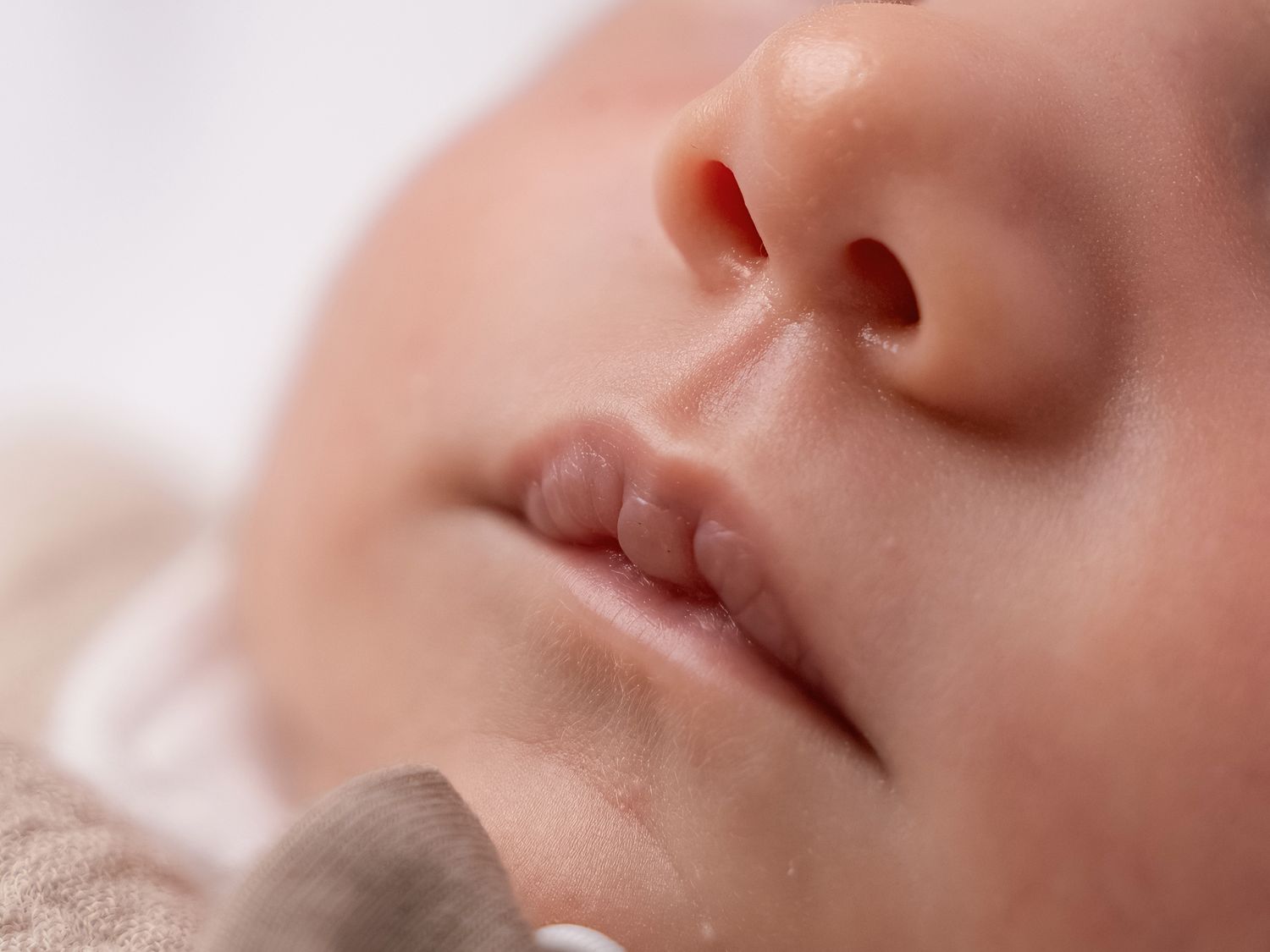 Close-up of a peaceful sleeping newborn baby's face with soft skin and delicate features.