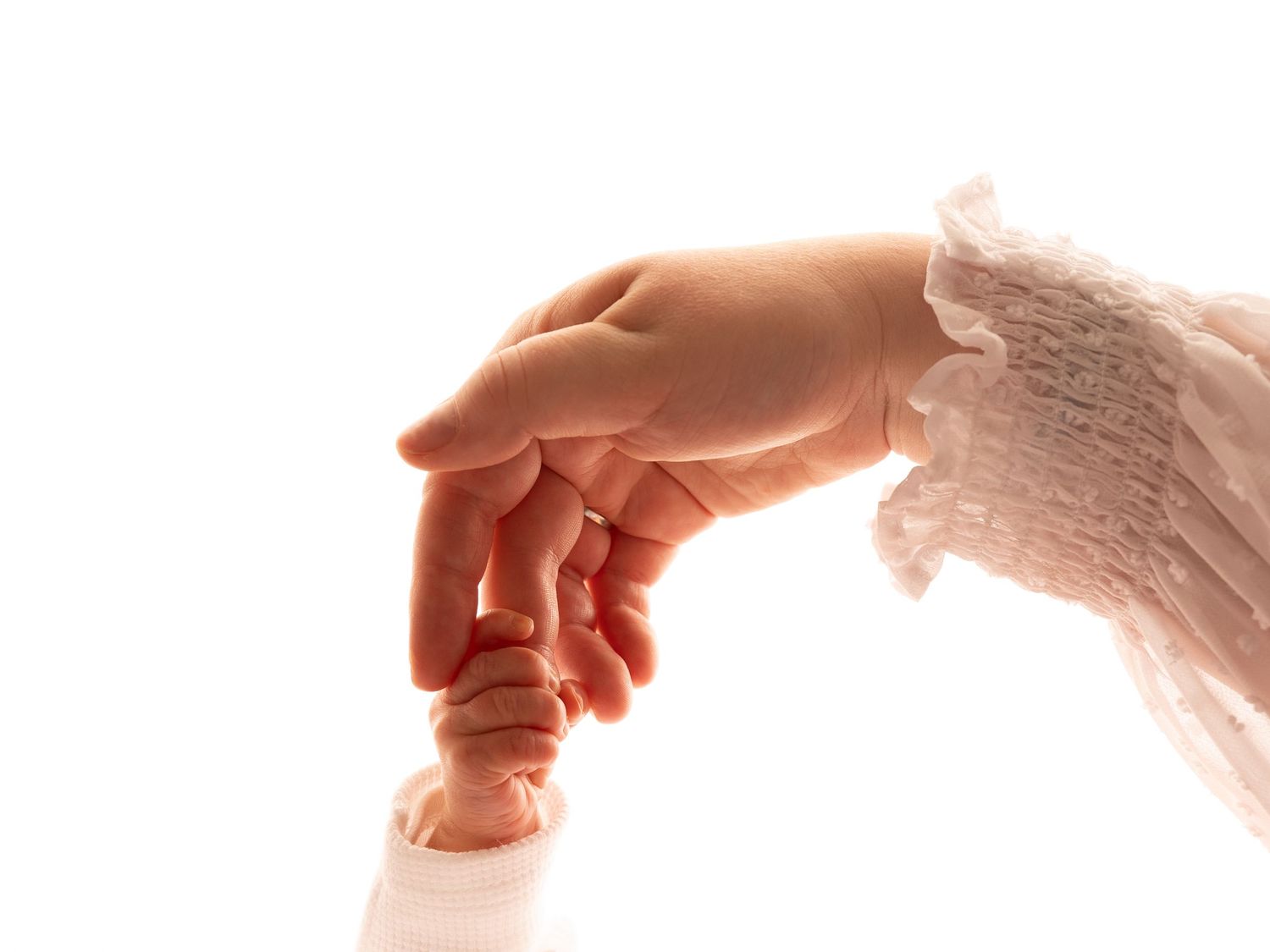 Adult hand gently holding a tiny newborn baby's hand, symbolizing love and new life.