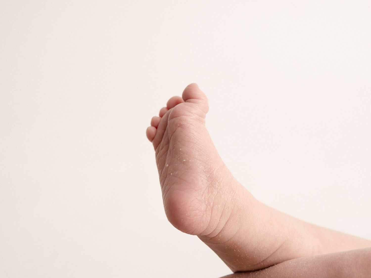 Close-up of newborn baby tiny foot and toes against a clean white background.