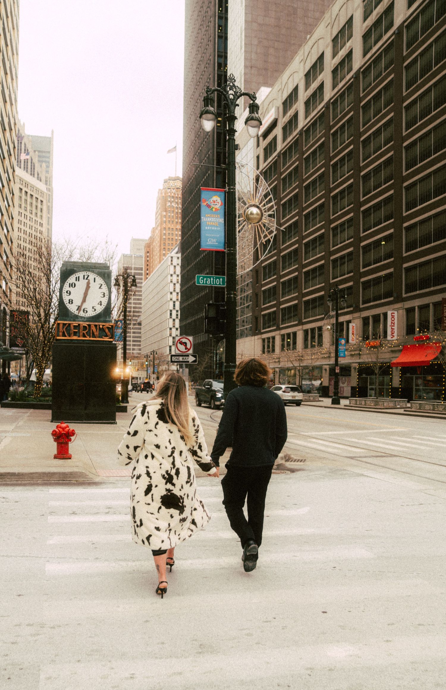 A couple walking through an urban cityscape with tall buildings and empty streets.