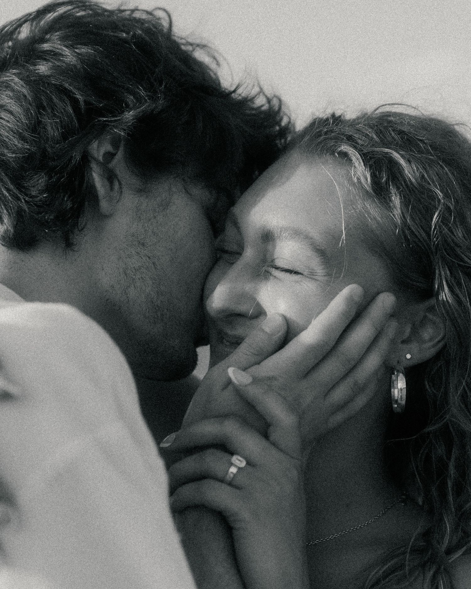 Black and white photo of a romantic couple sharing an intimate moment, man tenderly holding womans face as they lean close.