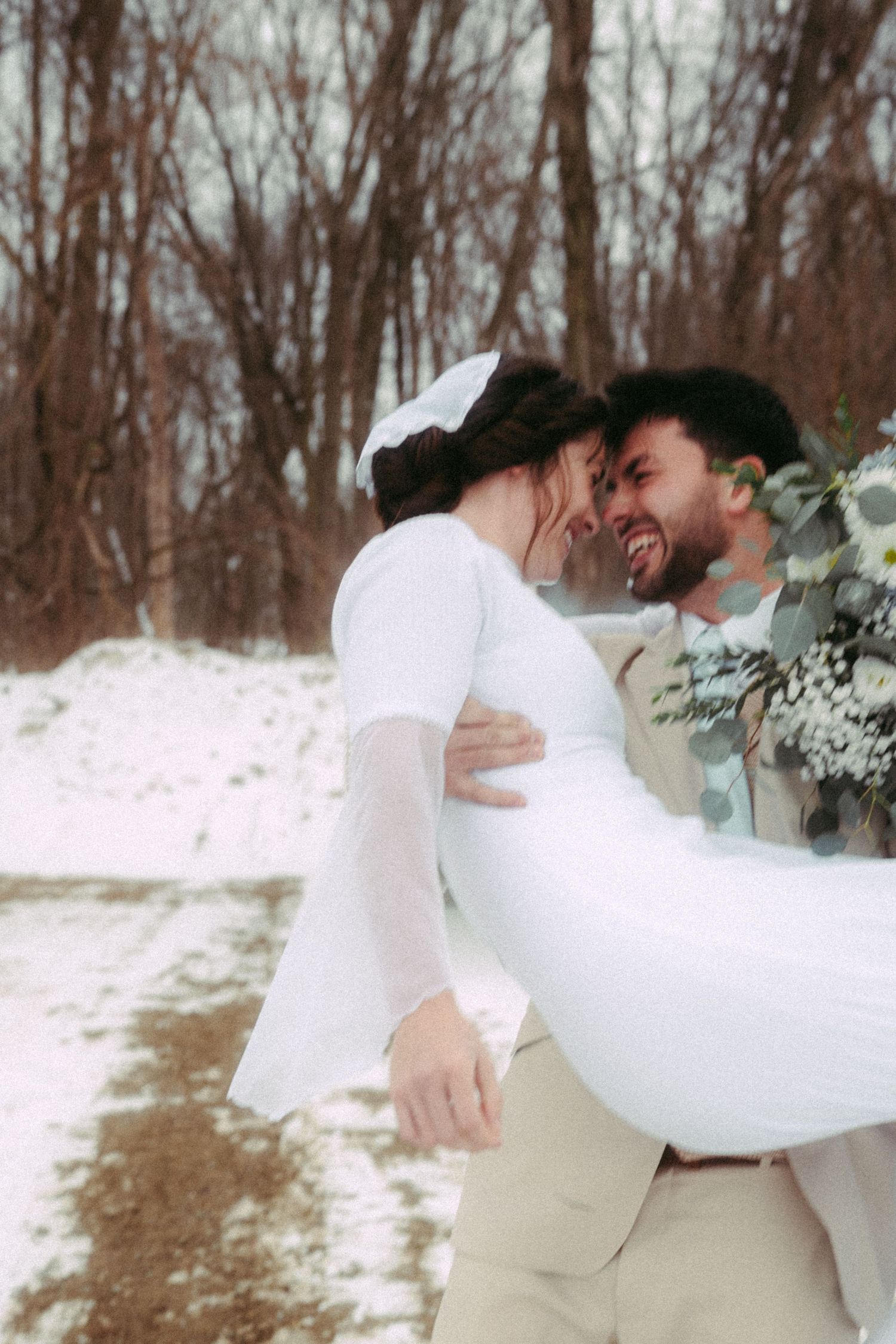A winter wedding couple shares a romantic moment in the snow.