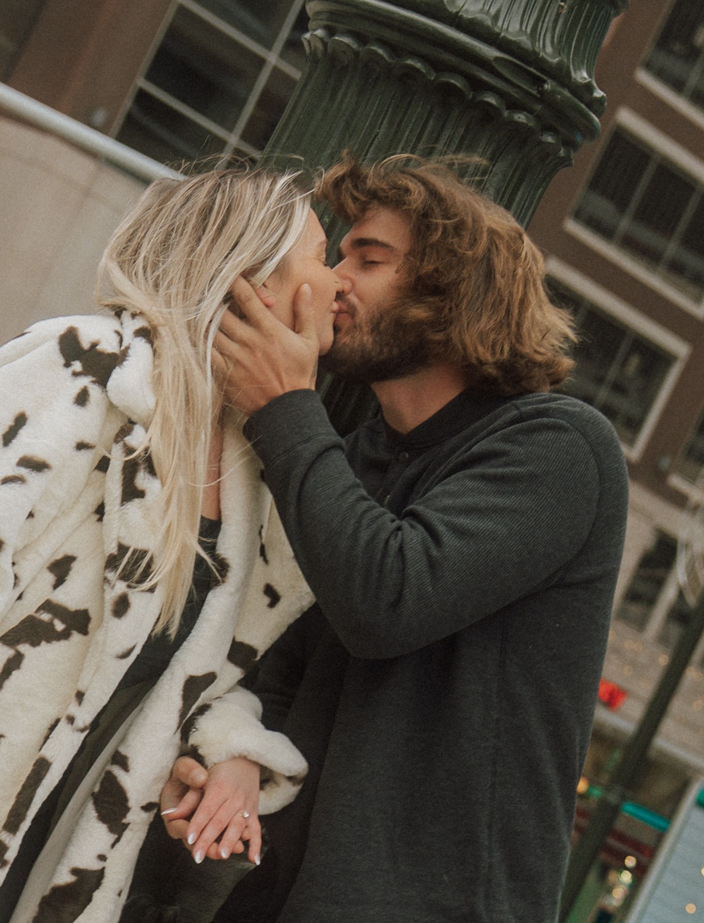 A romantic couple sharing an intimate kiss in a casual outdoor setting.