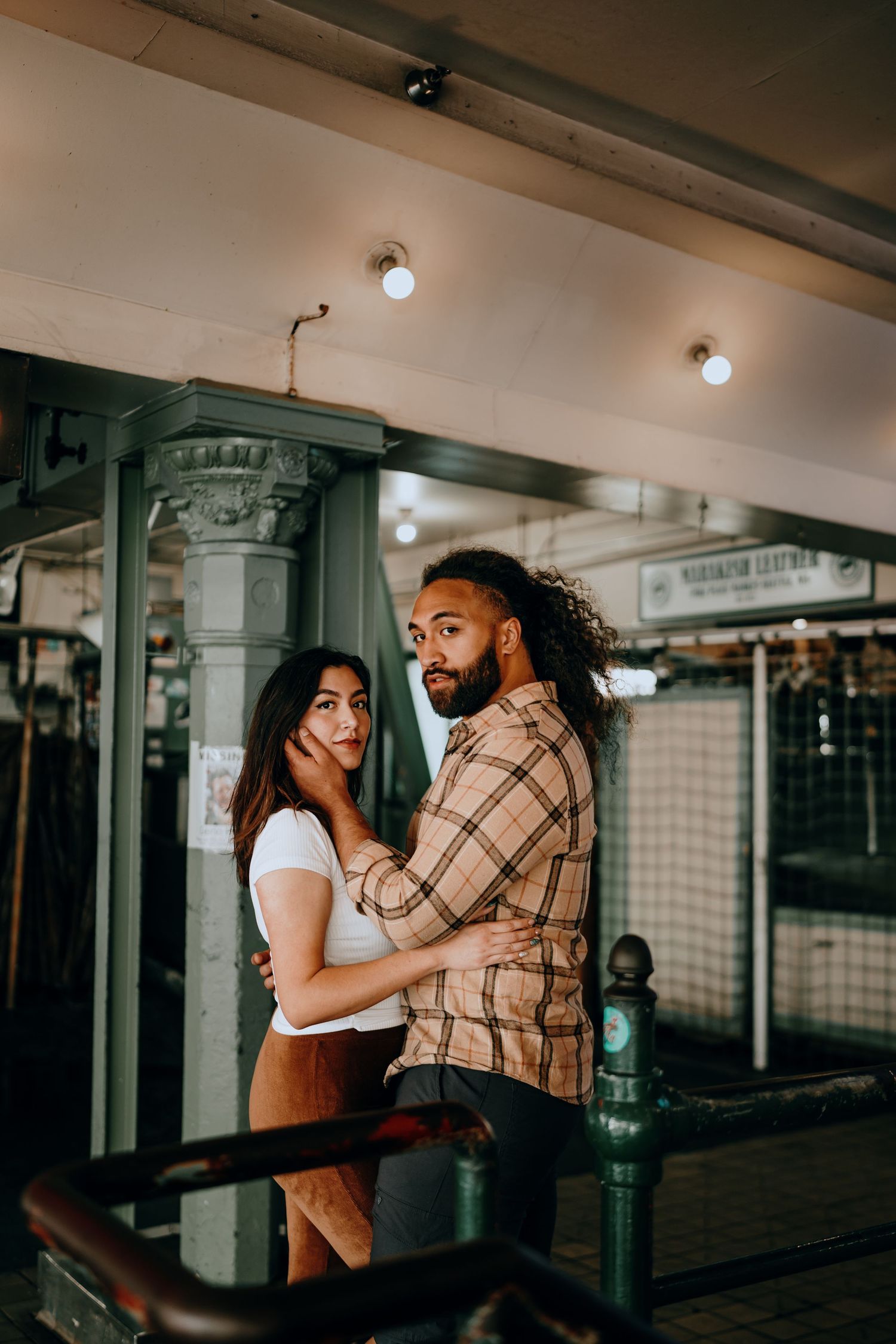 Couple sharing an intimate embrace under warm lights at Pike Place Market in Seattle.