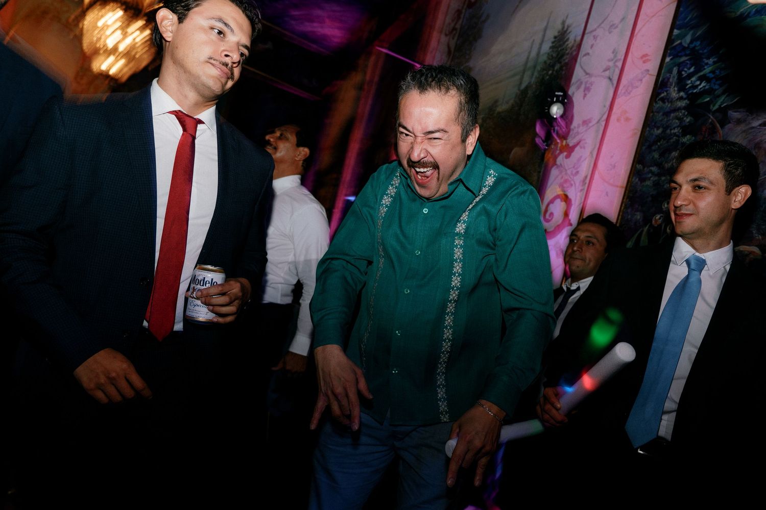 Guests laughing and dancing at festive wedding reception celebration.