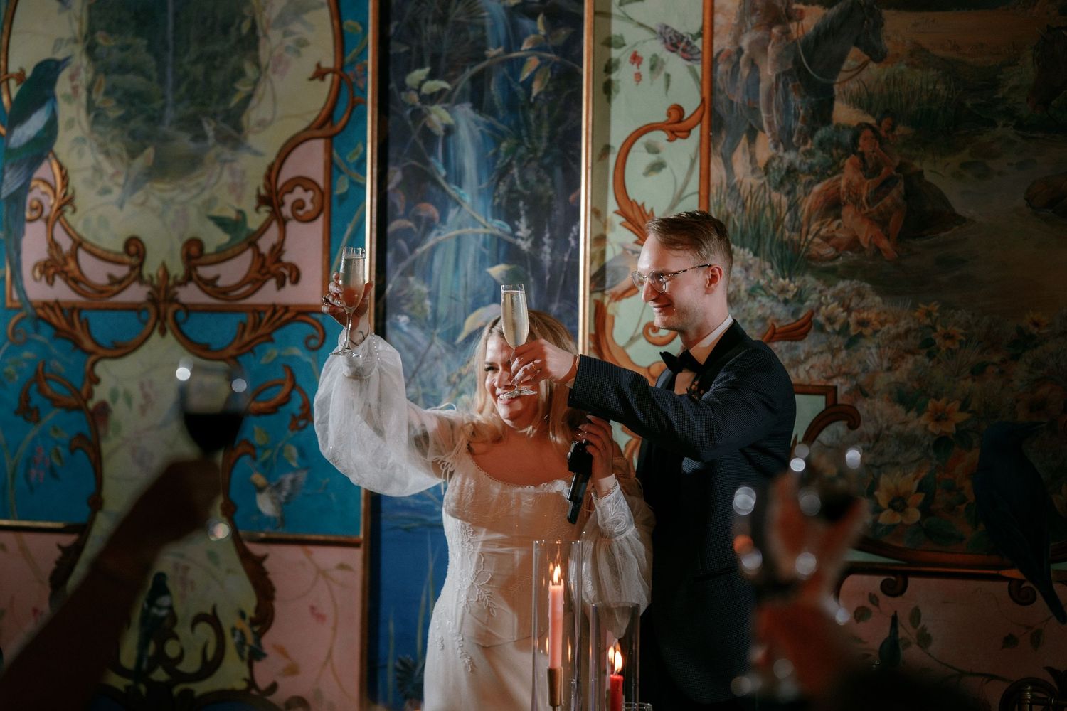 Bride and groom lighting candles together at elegant wedding ceremony with ornate decor.