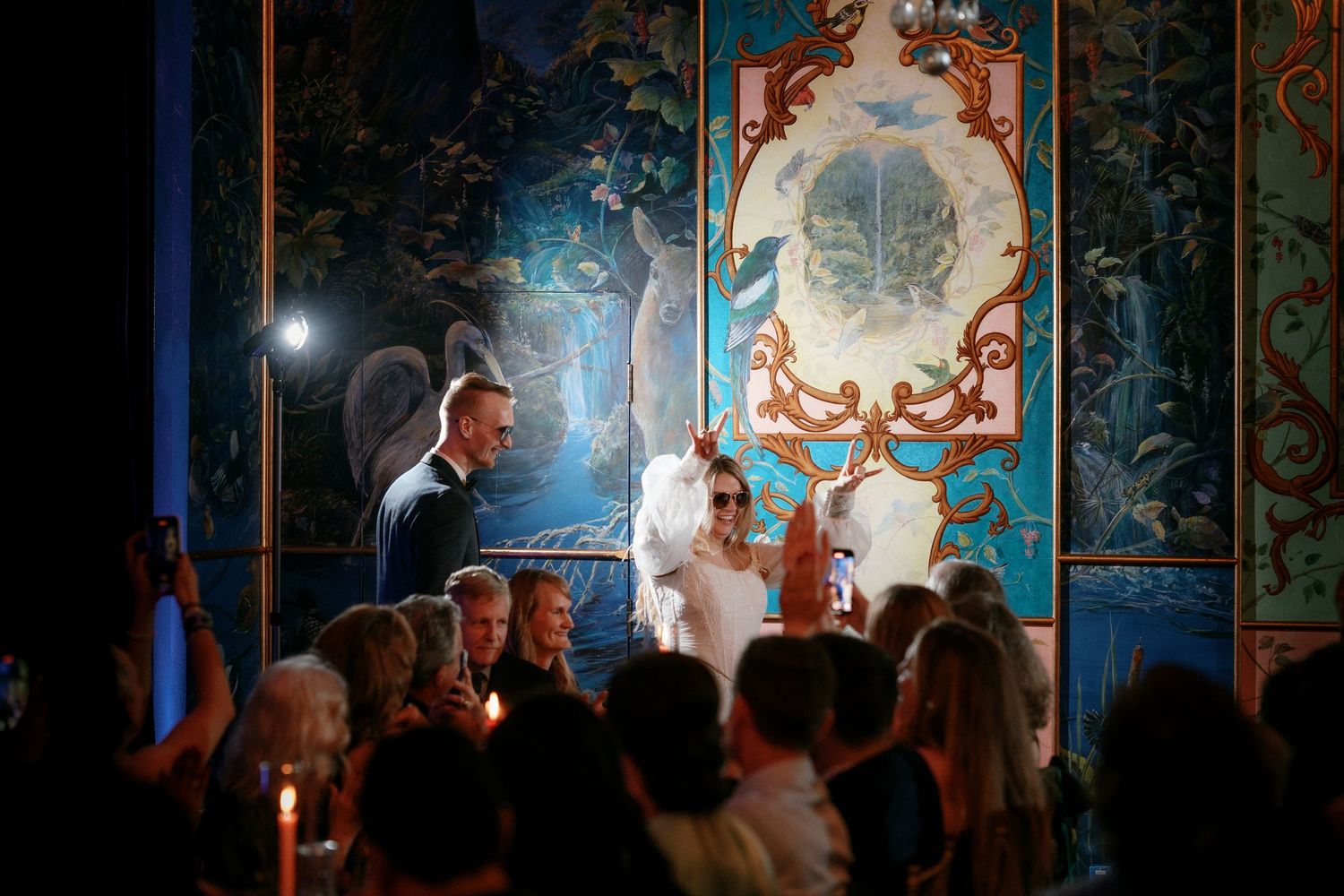 Bride and groom at candlelit wedding ceremony before ornate blue decorative backdrop.