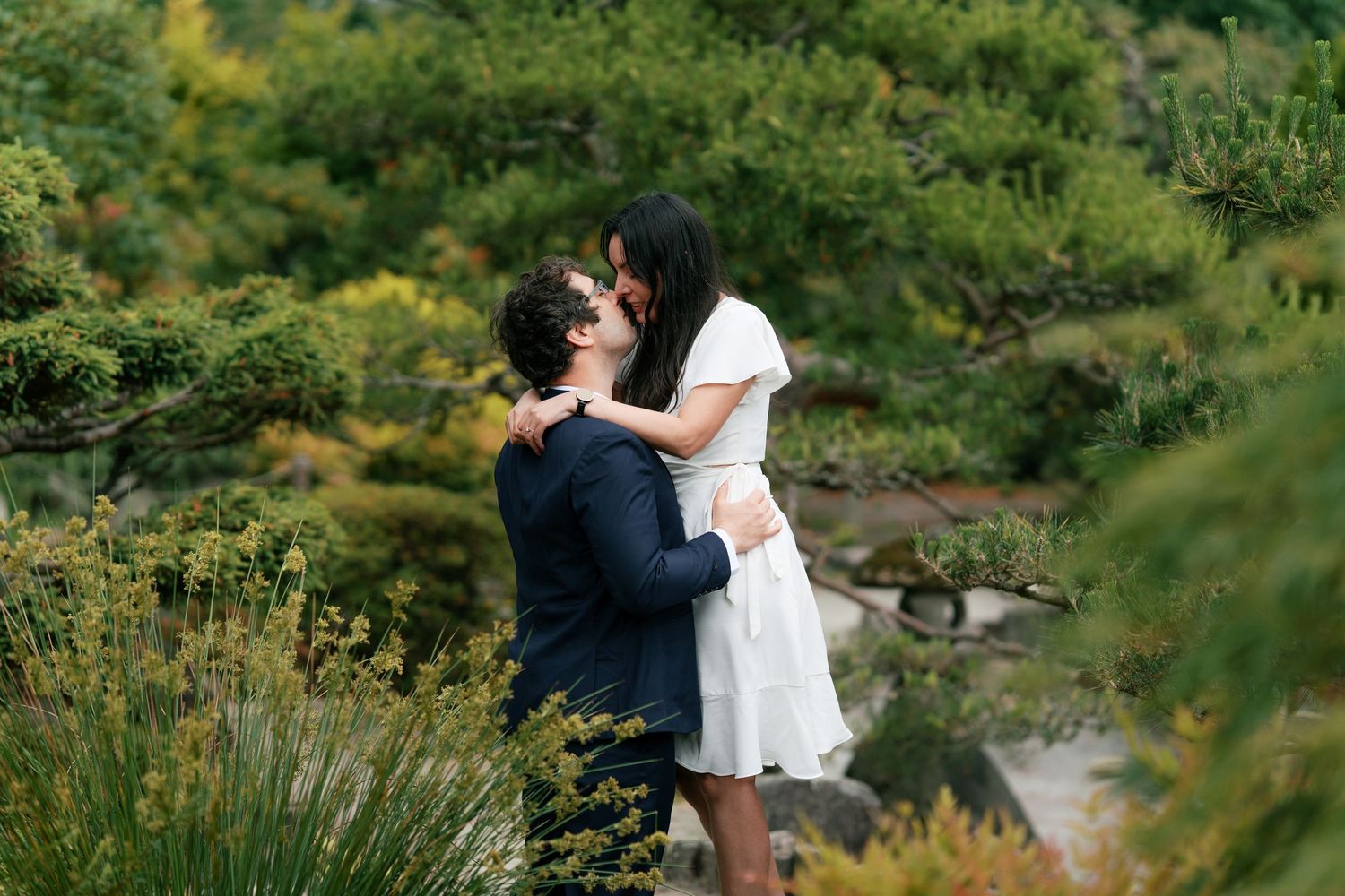 Couple sharing a romantic moment in a lush green garden during their engagement session.