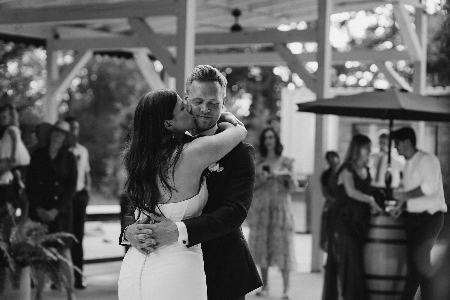 Black and white photo of bride and groom sharing a romantic kiss during first dance.