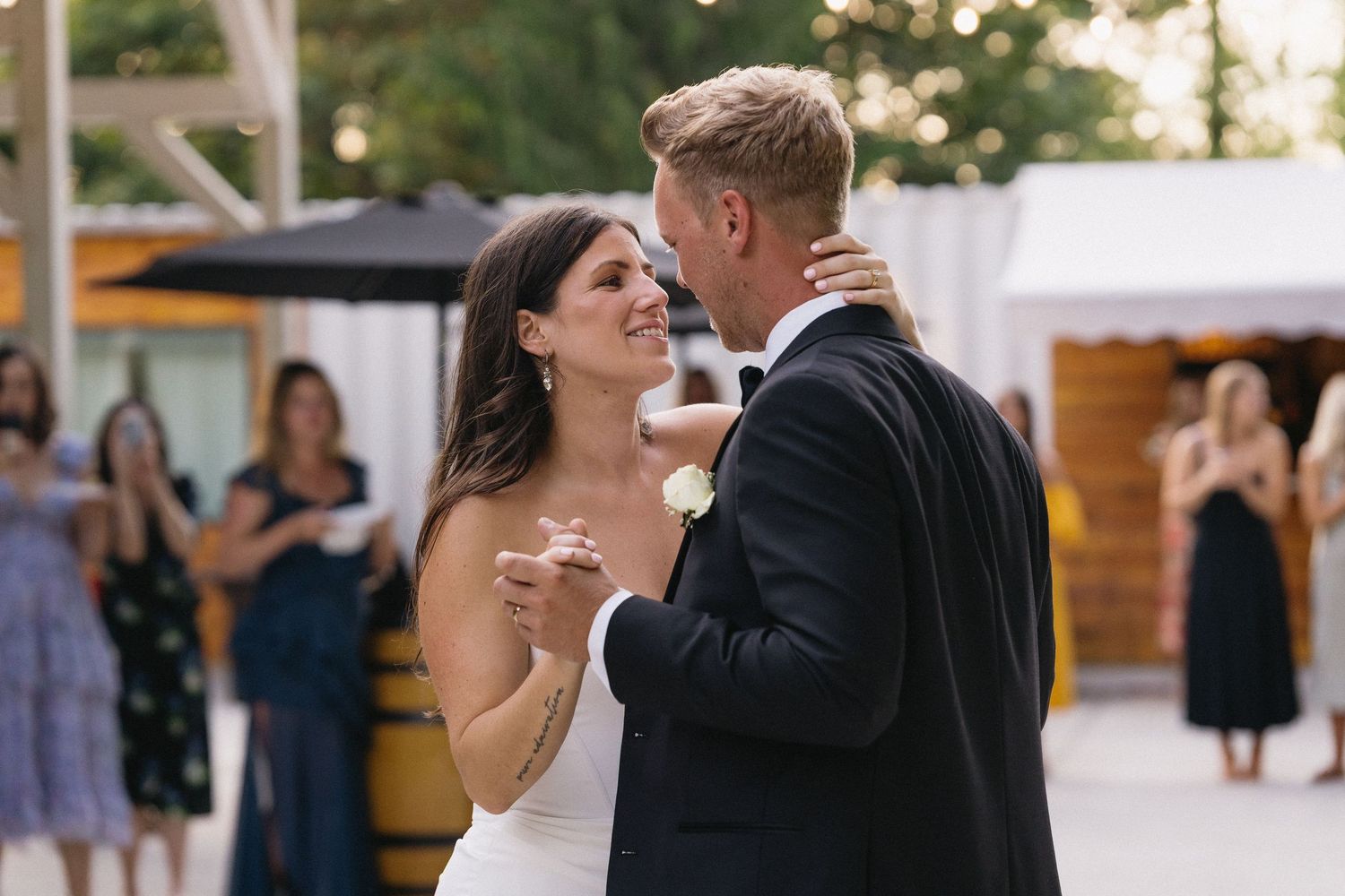 Bride and groom sharing their first dance outdoors, gazing lovingly at each other.