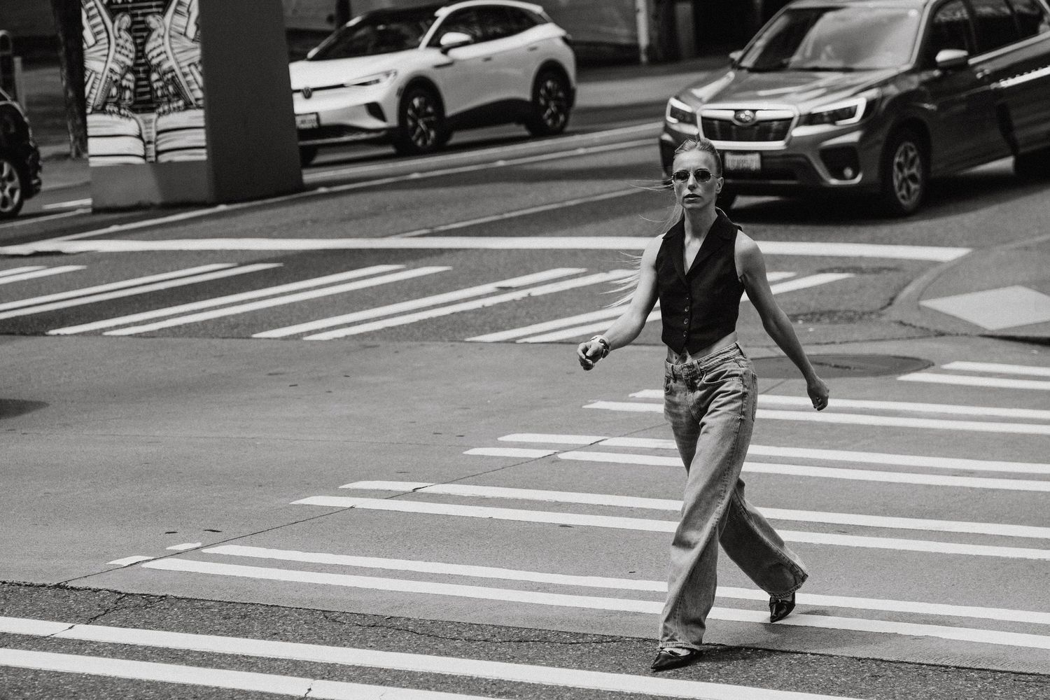 Stylish woman crossing urban street in black and white street photography shot.