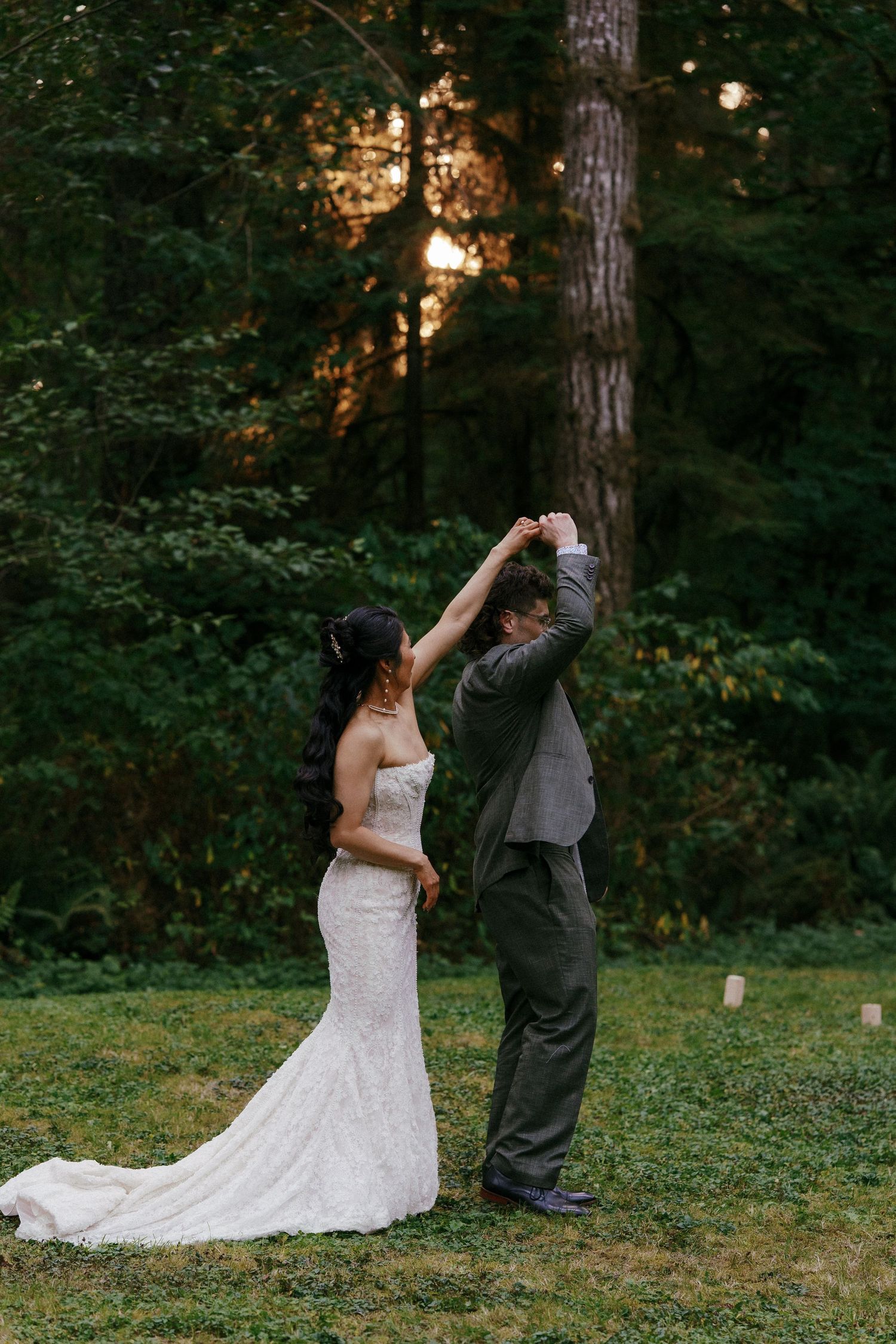 Bride and groom dance together at golden sunset in a lush green forest clearing during their wedding.