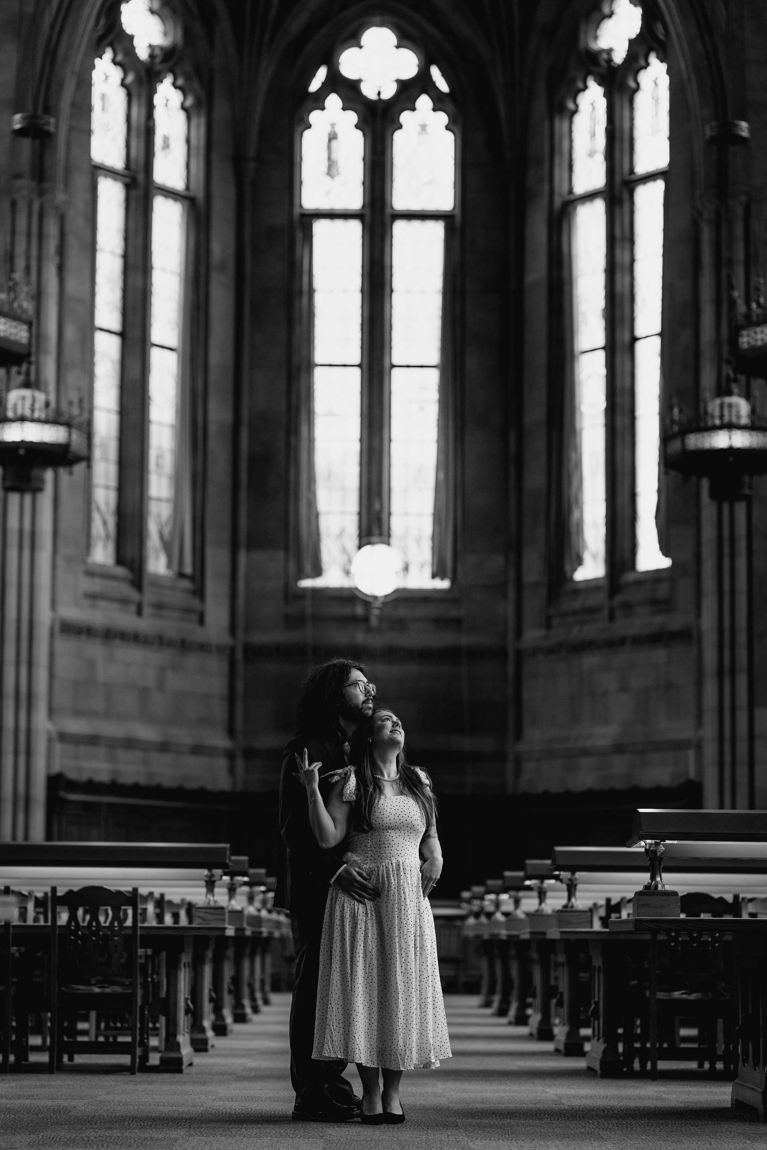 Romantic black and white photo of a couple embracing in a stunning gothic cathedral interior.