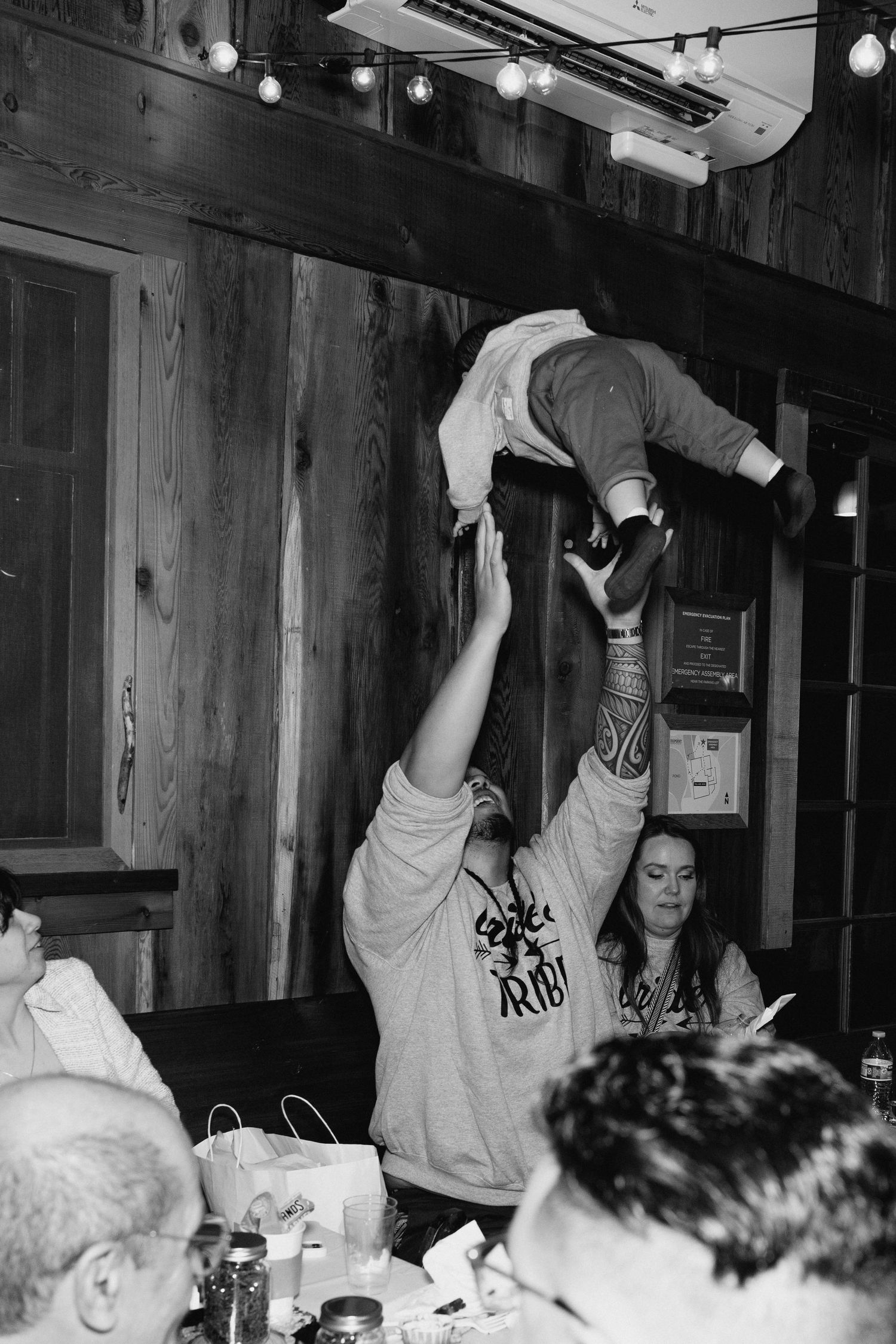 Guest playfully lifting a child above their head at a casual indoor wedding celebration event.