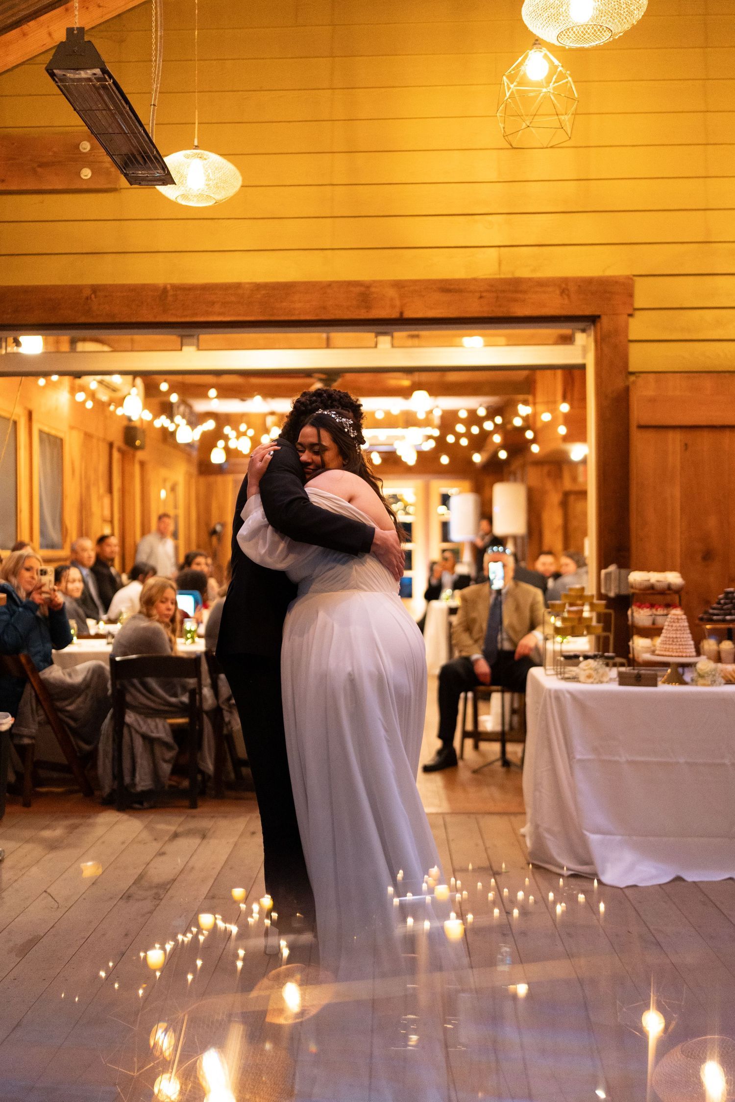Bride and groom share an emotional first dance embrace surrounded by candlelight on the dance floor at their barn wedding.