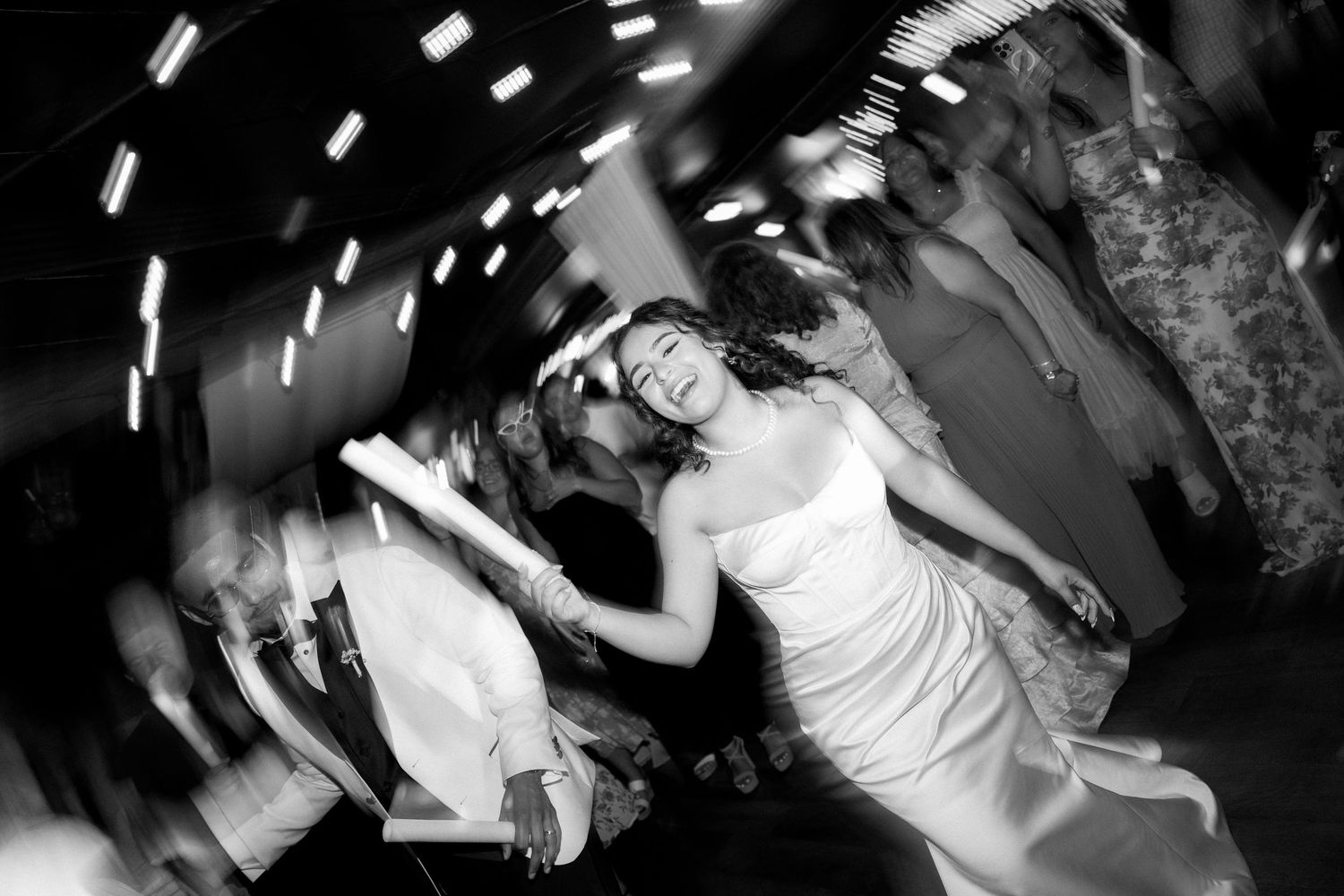 Black and white photo of a joyful bride dancing energetically at her wedding reception celebration.
