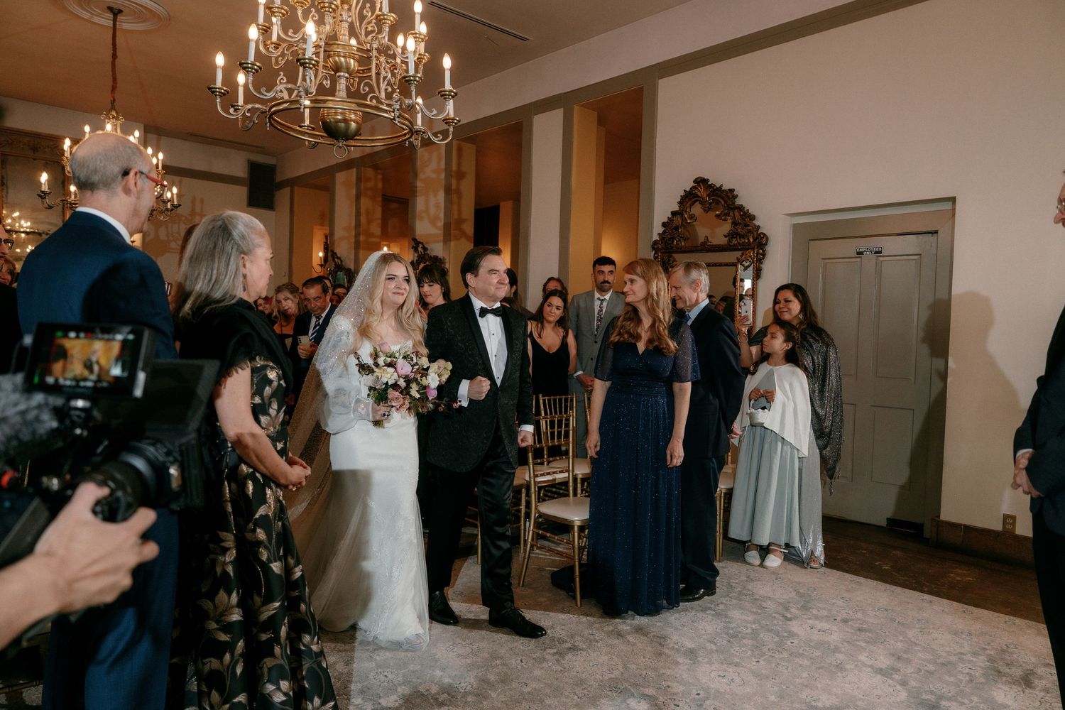 Bride and groom walk back down the aisle after their wedding ceremony surrounded by guests and bridesmaids.