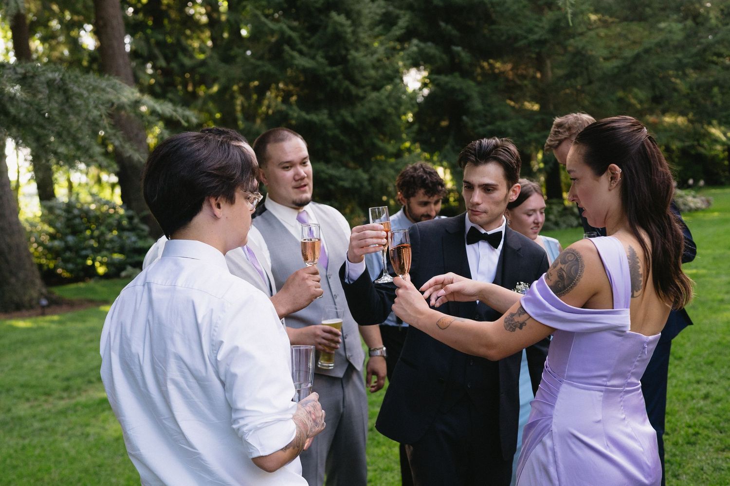 Wedding guests in formal wear toasting with champagne glasses in an outdoor garden setting.