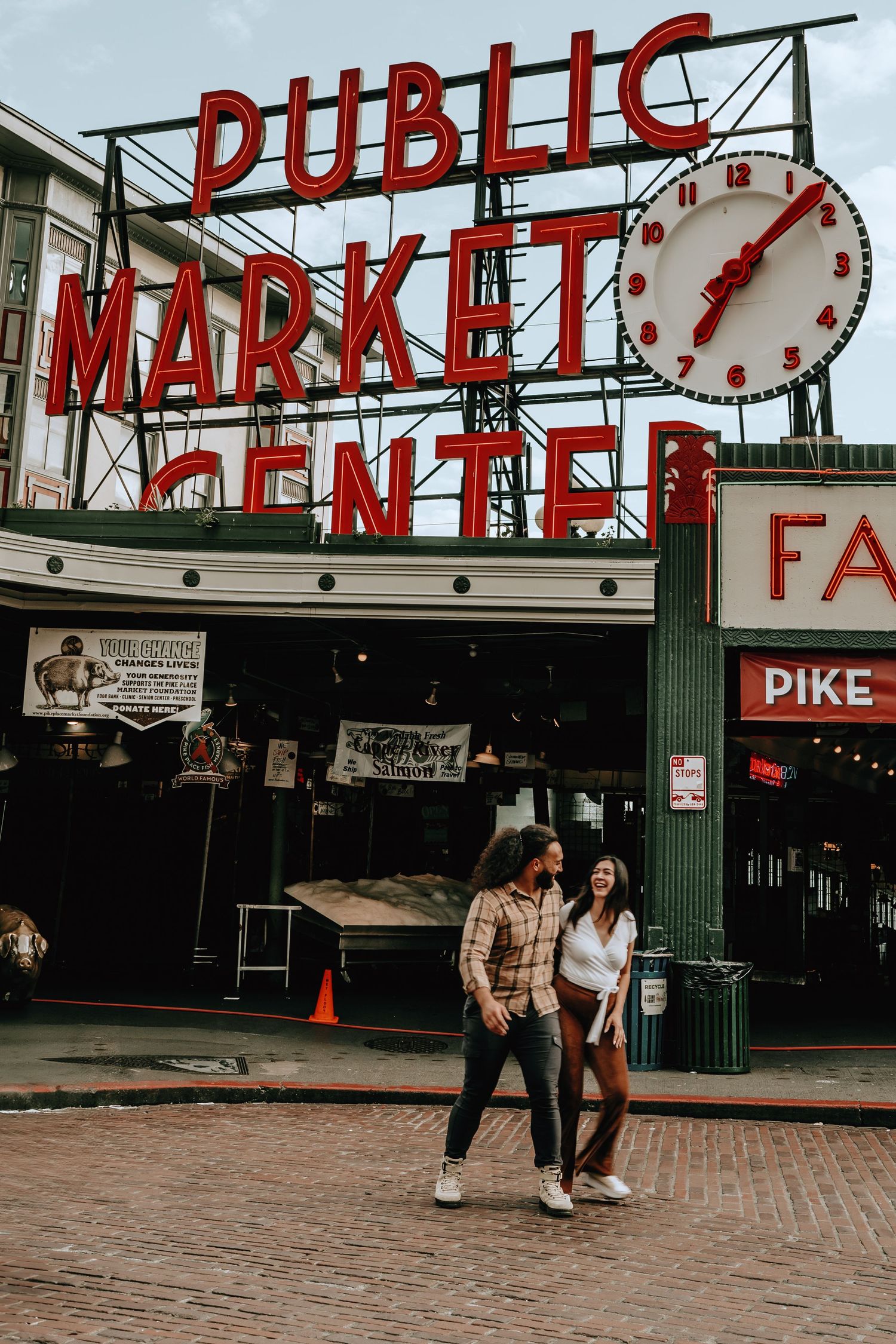 Happy couple walking hand in hand in front of Pike Place Public Market Center in Seattle.
