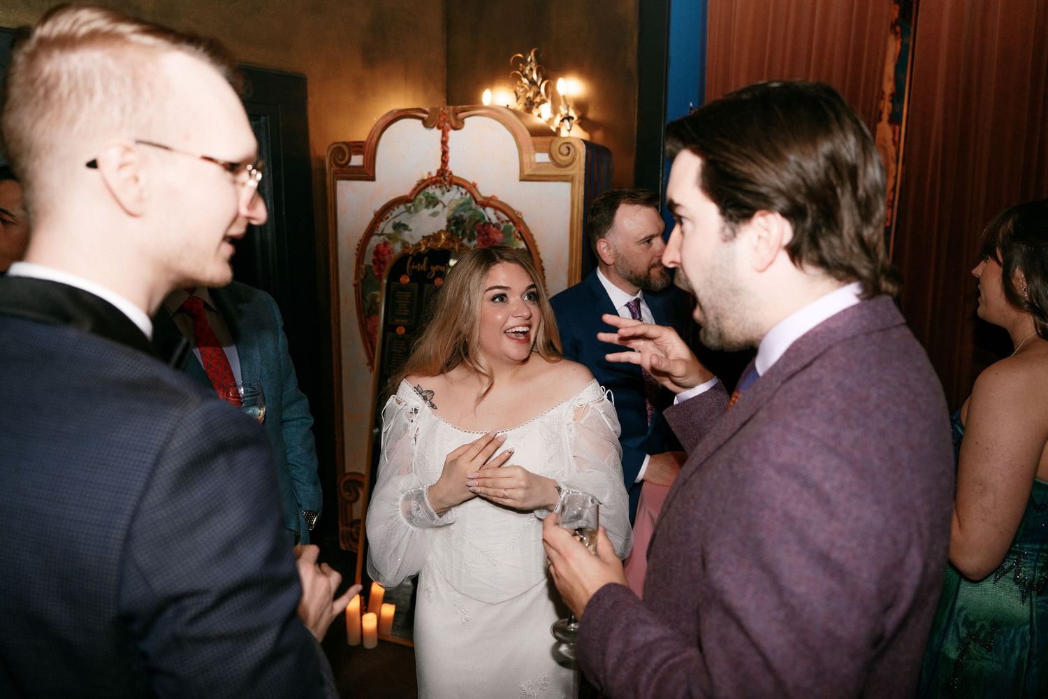 Bride in white dress laughing with wedding guests during reception celebration.