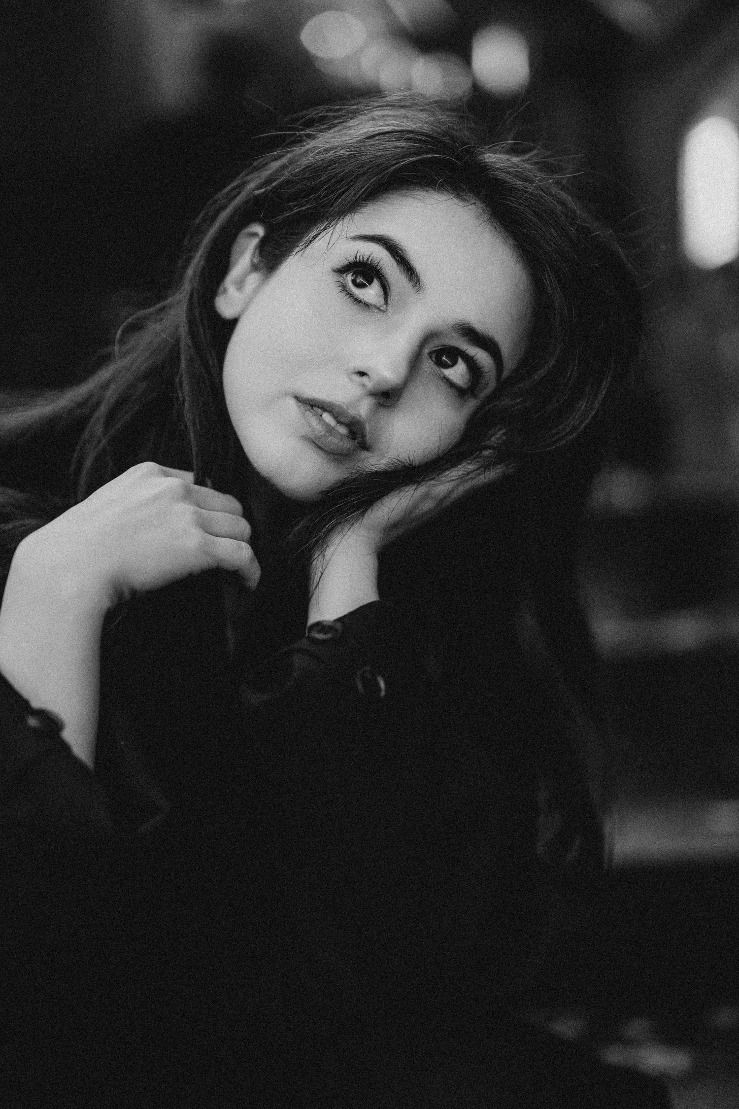 Black and white close-up portrait of young dark-haired woman in black jacket looking at camera.