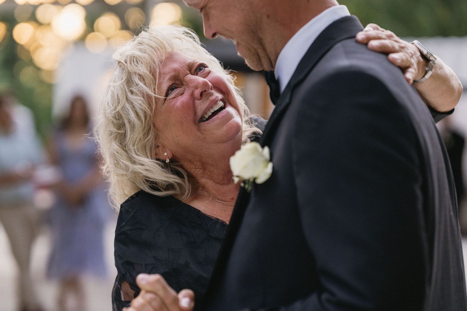 Emotional mother son wedding dance with tearful mom embracing groom in tuxedo at reception.