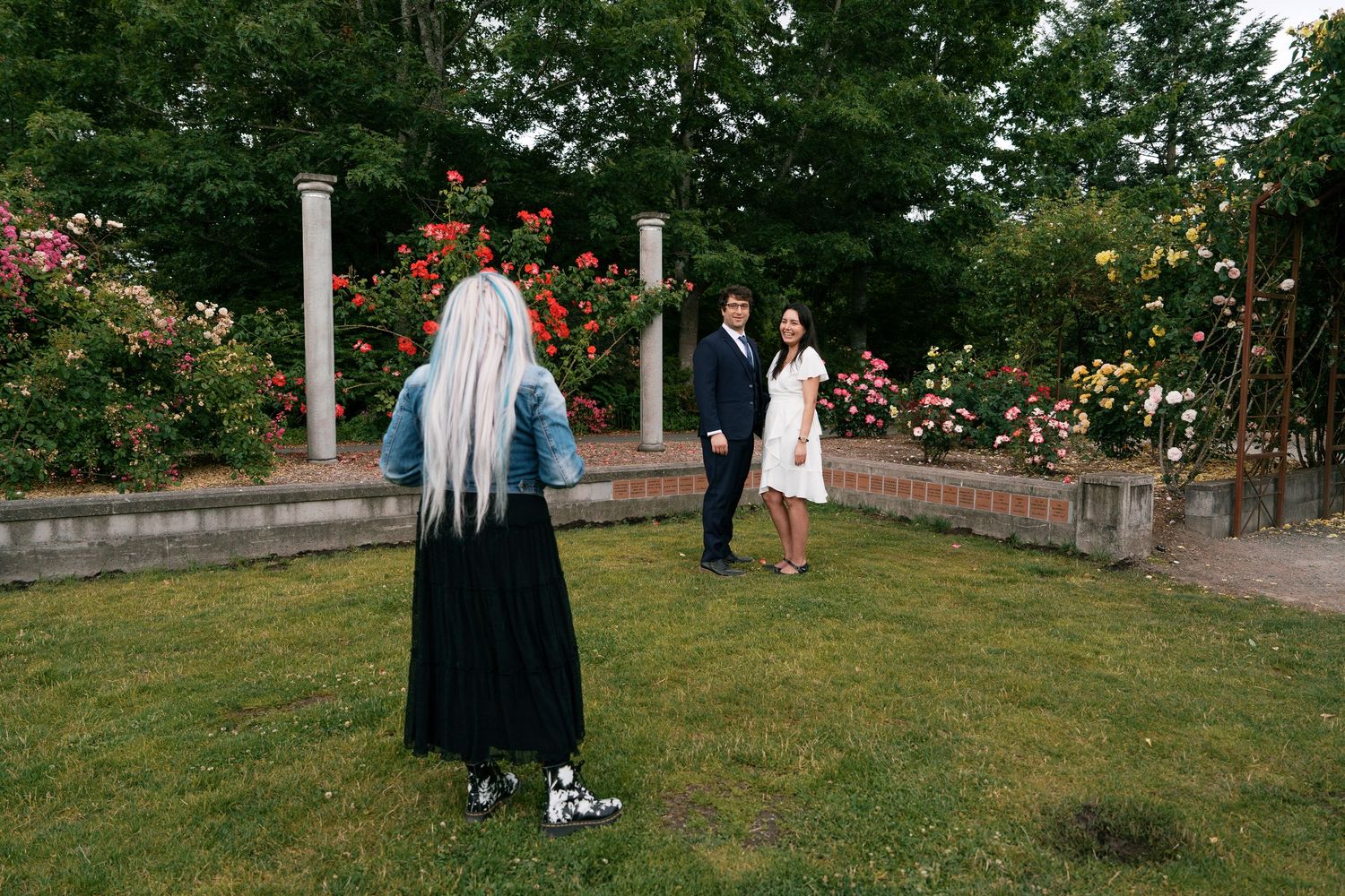 Photographer capturing couple posing in a colorful rose garden during outdoor photo session.