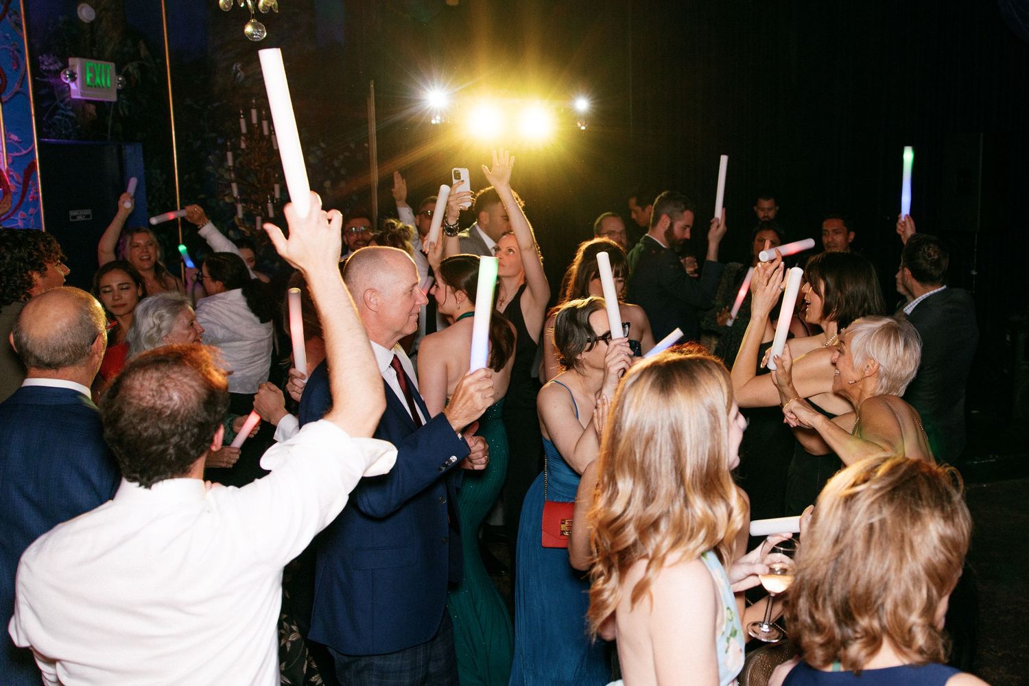 Wedding guests raising glow sticks during a lively celebration on the dance floor.