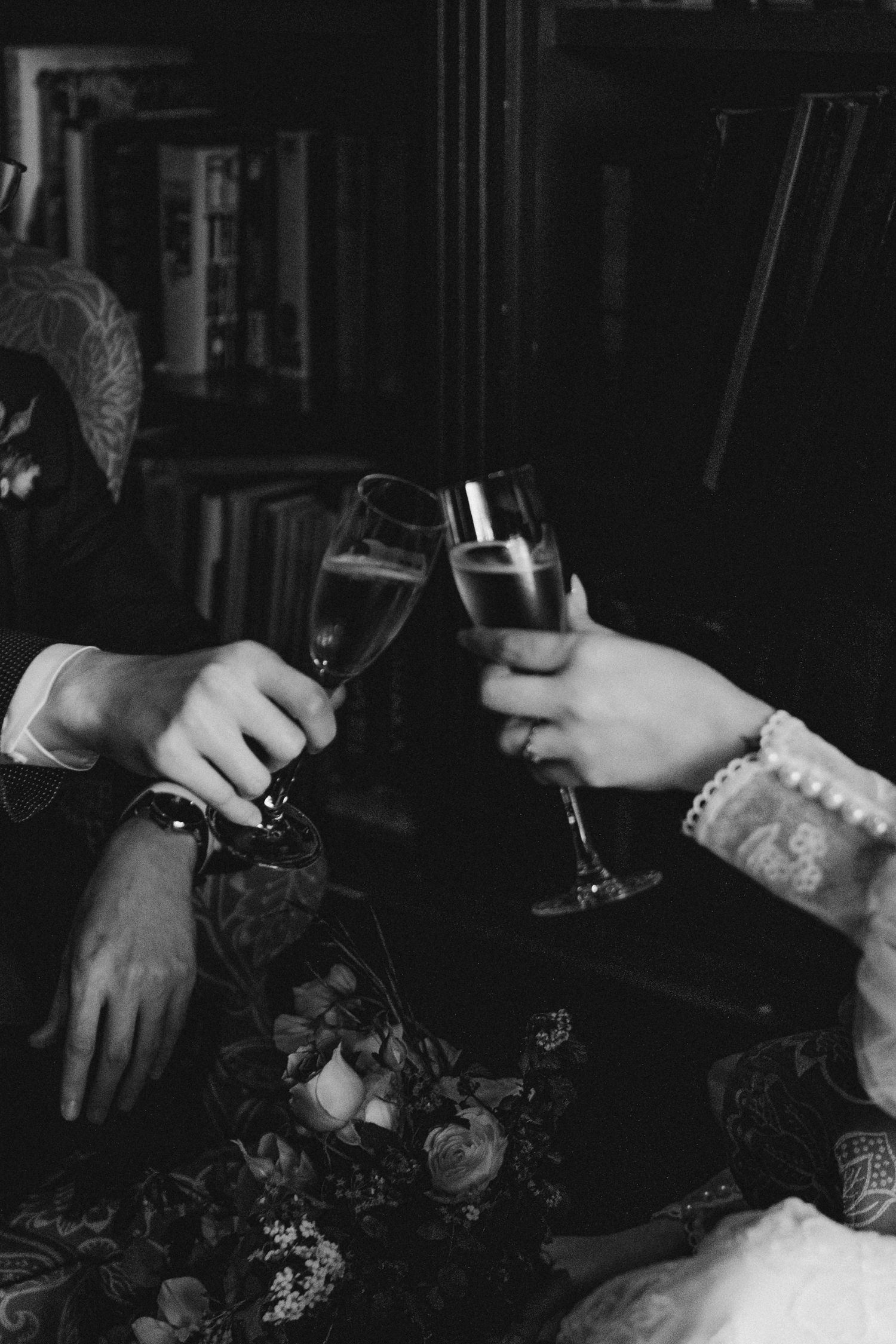 Bride and groom toasting with champagne flutes in a moody black and white wedding photo.