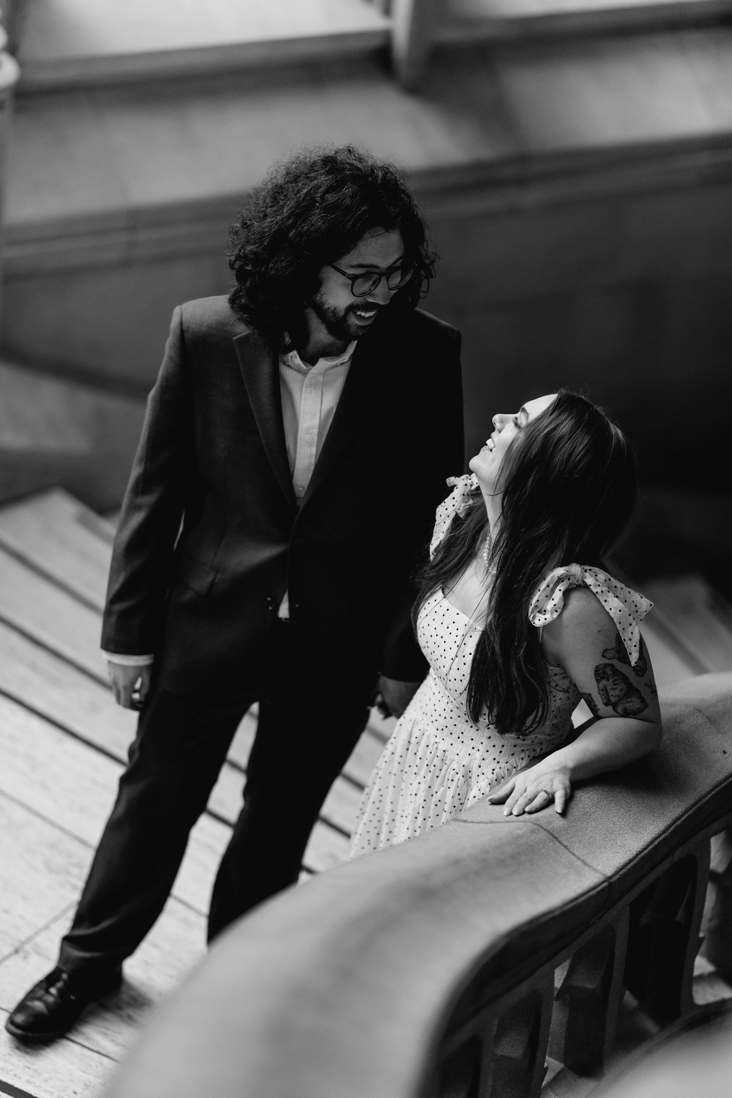 Black and white overhead shot of a couple laughing together on a grand staircase.