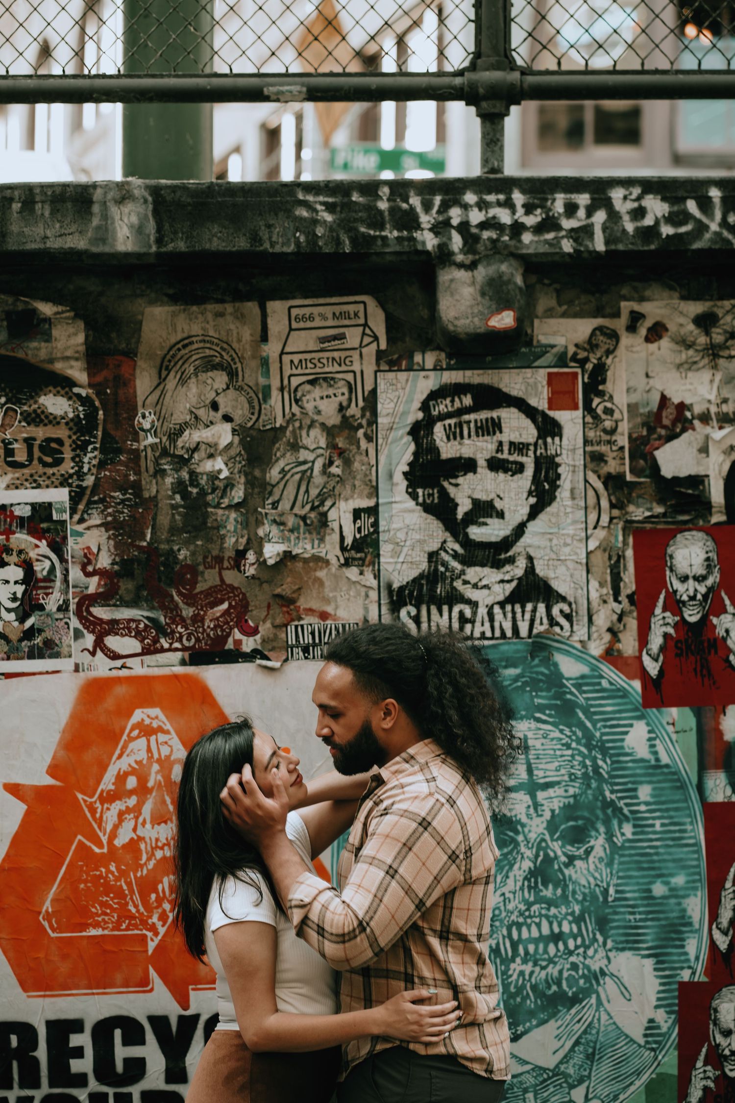 Couple sharing a tender moment in front of a graffiti and street art covered urban wall.